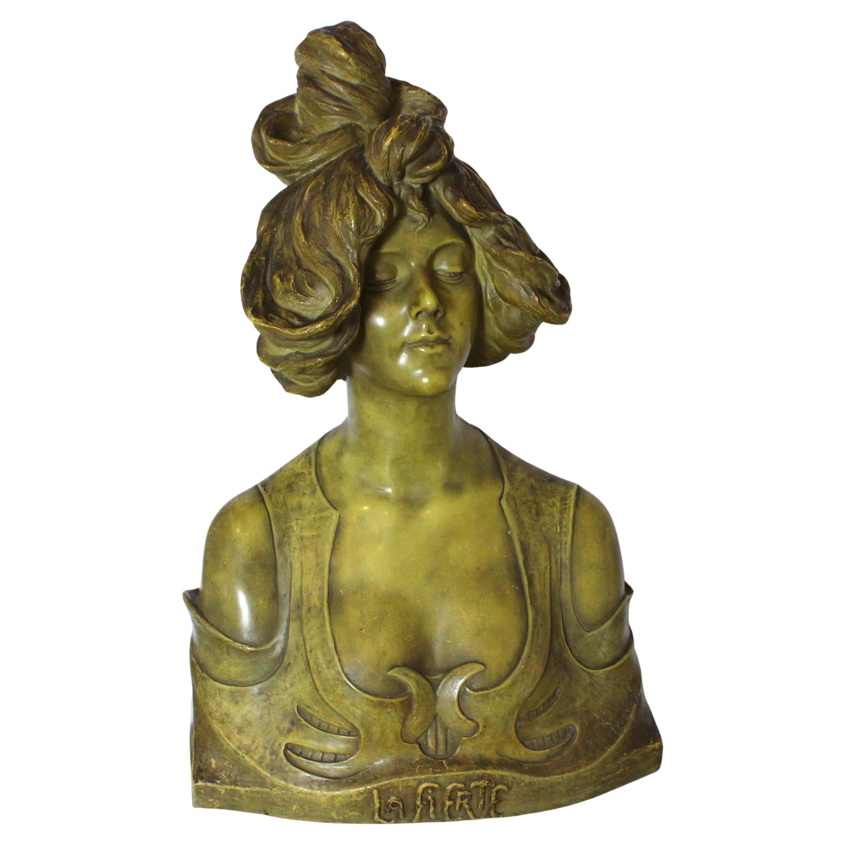This stylish, chic and large scale bust of a young woman dates to the Art Nouveau period and was acquired from a Palm Beach estate. The sculptor was B. Haniroff, and it is fabricated in terracotta with a soft green translucent, patinated glaze.
