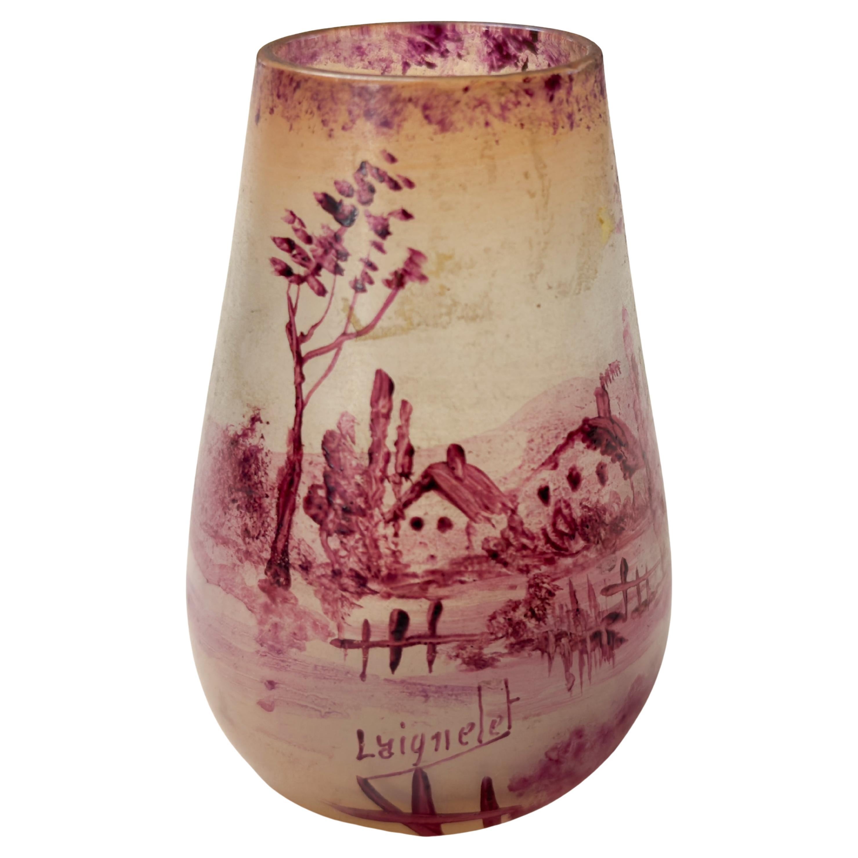 Pequeño y encantador jarrón de cristal Art Nouveau de la Verrerie de Laignelet, con una escena panorámica de la región de Bretaña pintada al frío en un delicado color rosa. 
El jarrón está decorado con las características casas bretonas, ofreciendo