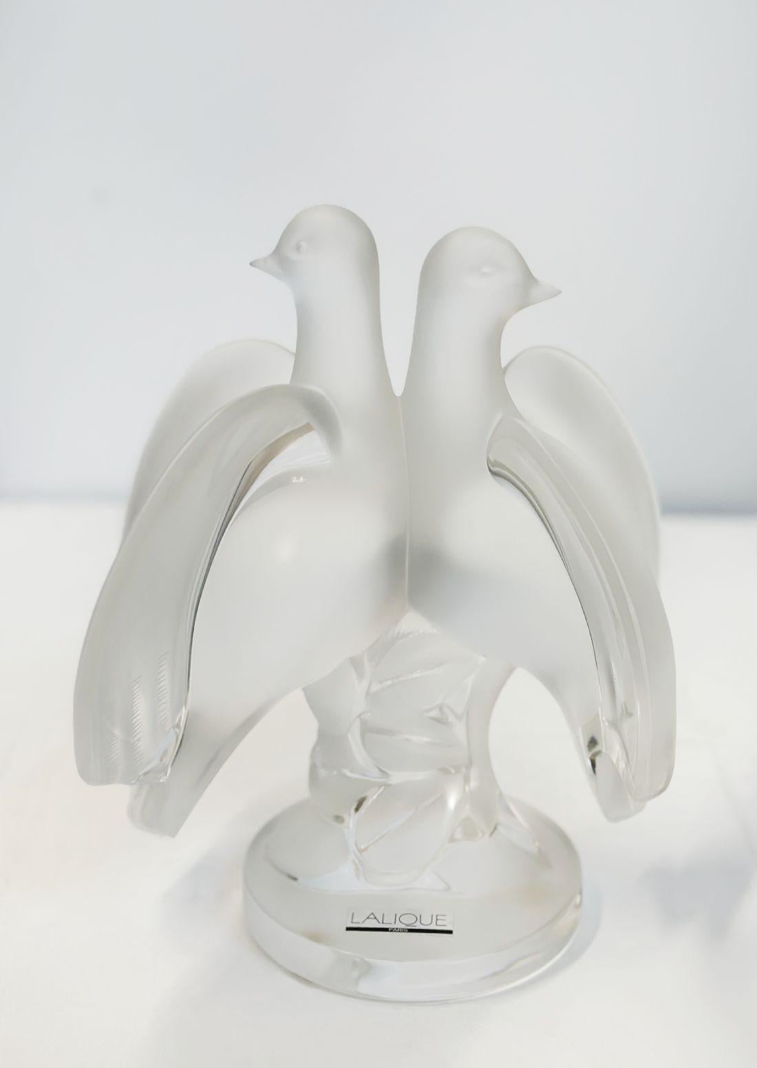 Graceful frosted glass figurine molded as two doves perched on a stylized leaf covered stem with their heads turned in the opposite direction, incorporating a circular plinth depicting a trunk with leaves that is supported by a clear round base with
