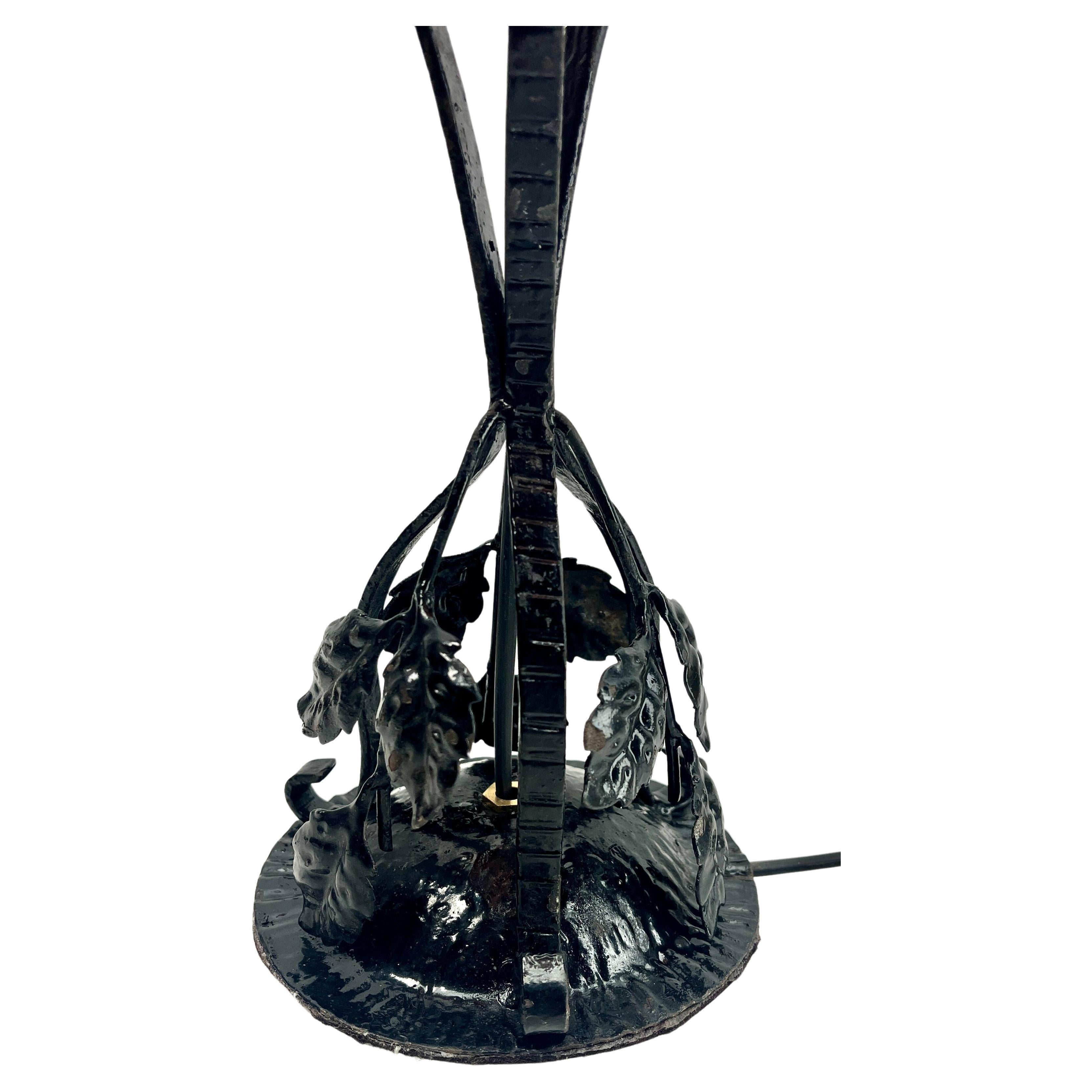 Anni '30, Belgio
Una meravigliosa lampada belga in stile Art Nouveau. 
Gli stand sono realizzati a mano in ferro battuto con finitura nera patinata e martellata con un motivo floreale. 
La lavorazione del metallo è di ottima qualità.
Coronata con