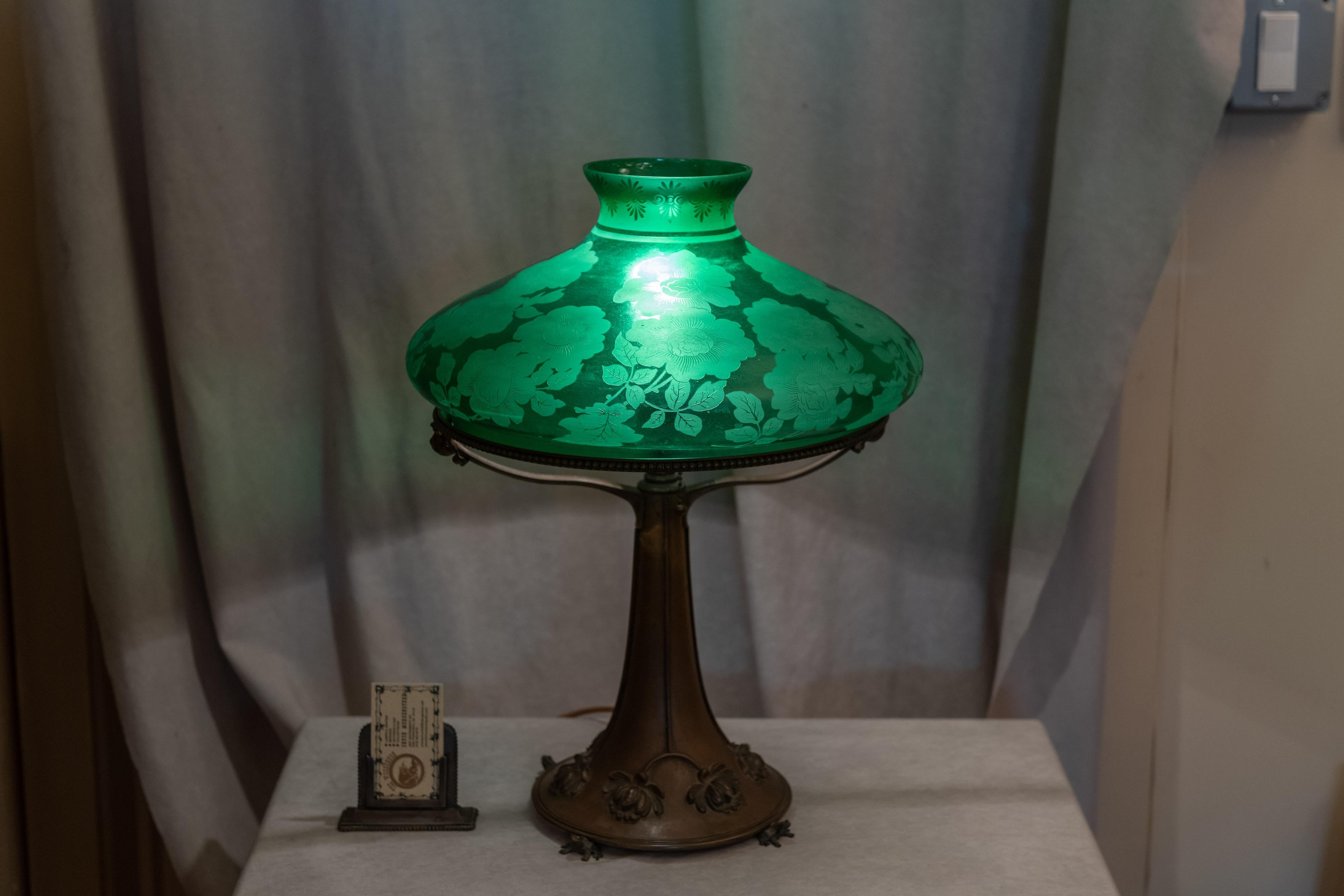 This lamp has a most unusual whimsical base with embossed flowers and 4 adorable frogs holding it up. The ring holding the shade is very strong and has bead work along the rim. The shade is a very high quality piece of glass with deep etched flowers