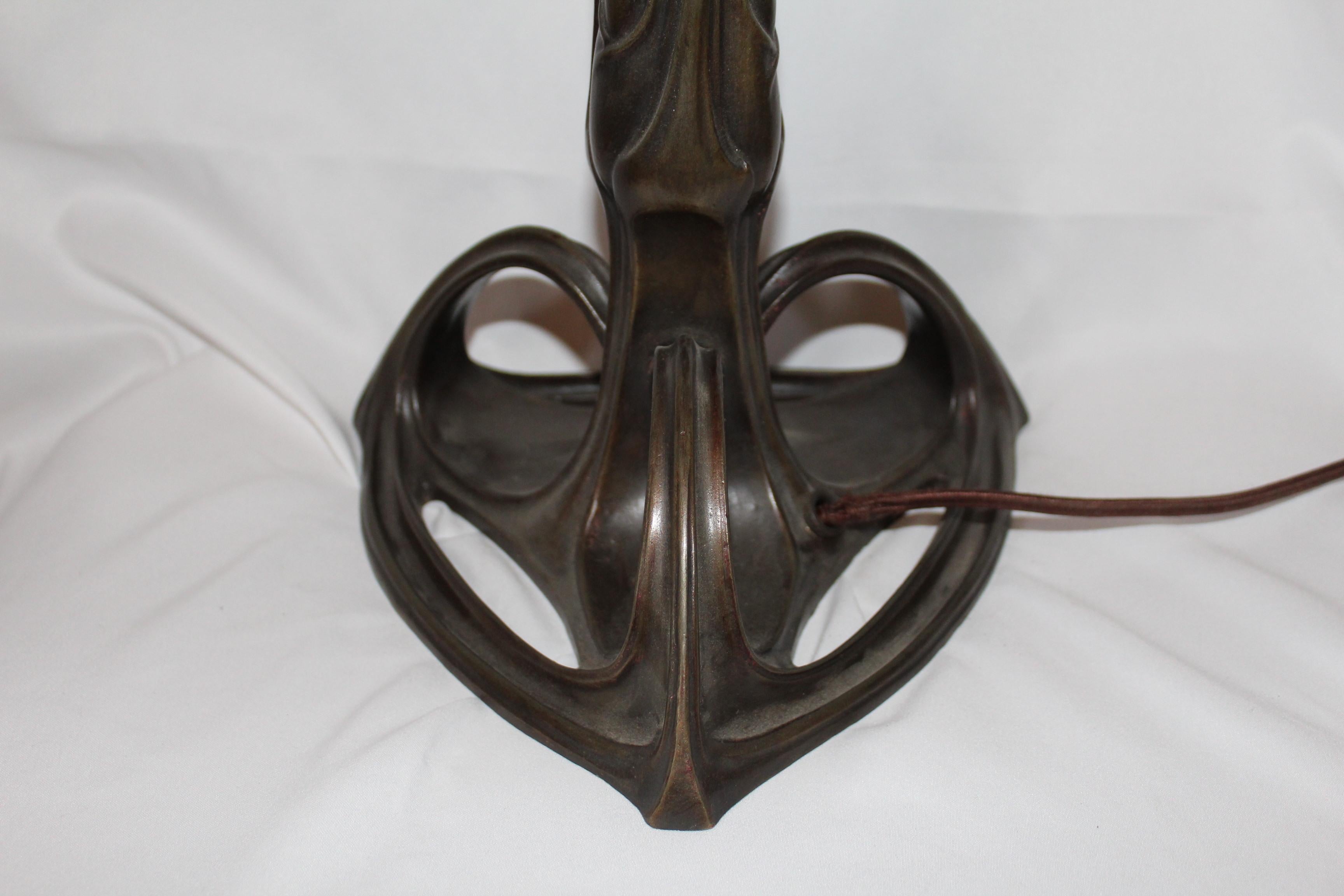 An Art Nouveau table lamp cast in bronze with 3-arm spider and single Edison socket. The Art glass shade is 13