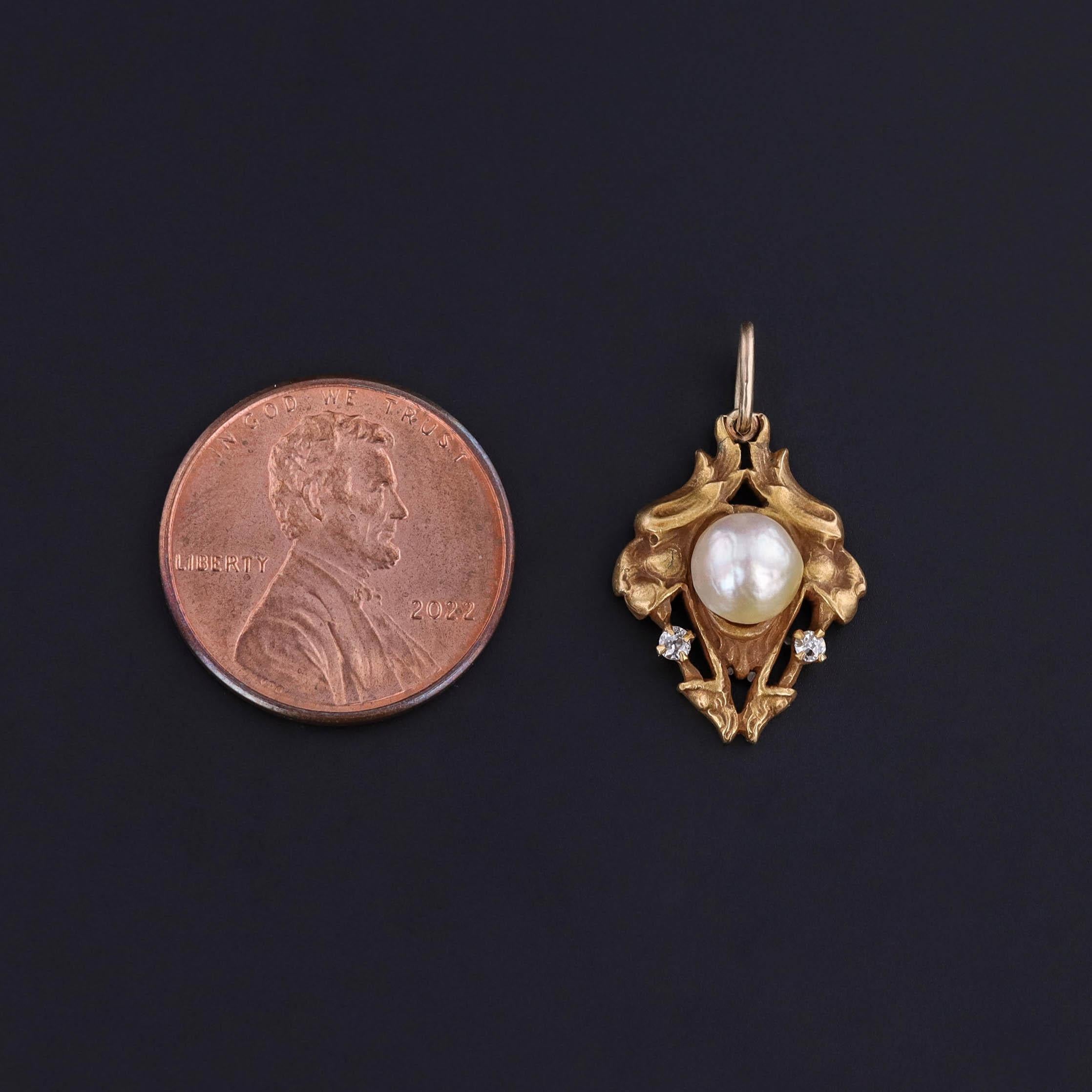 Cette délicieuse breloque Art Nouveau est ornée d'une perle blanche lustrée, complétée par deux diamants blancs taille unique et flanquée de part et d'autre de la tête de deux lions.

Fabriquée en 1900, cette pièce est en or massif 14k et mesure 0,9