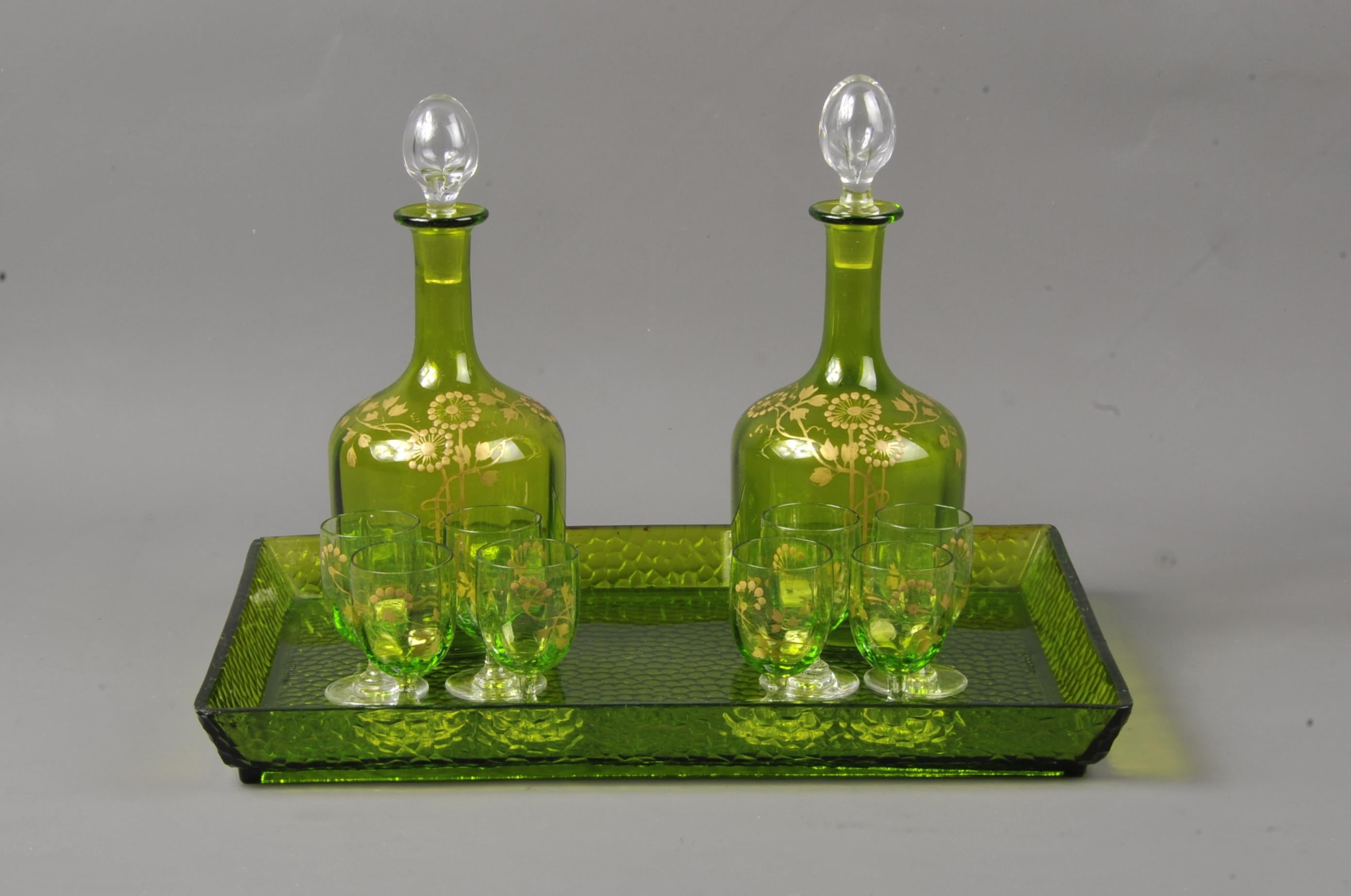 Lovely liquor service in green tinted crystal enhanced with Art Nouveau-inspired ornaments painted in fine gold, the carafe stoppers and the pedestals of the glasses are in clear crystal.

Composed of two carafes, eight glasses and a