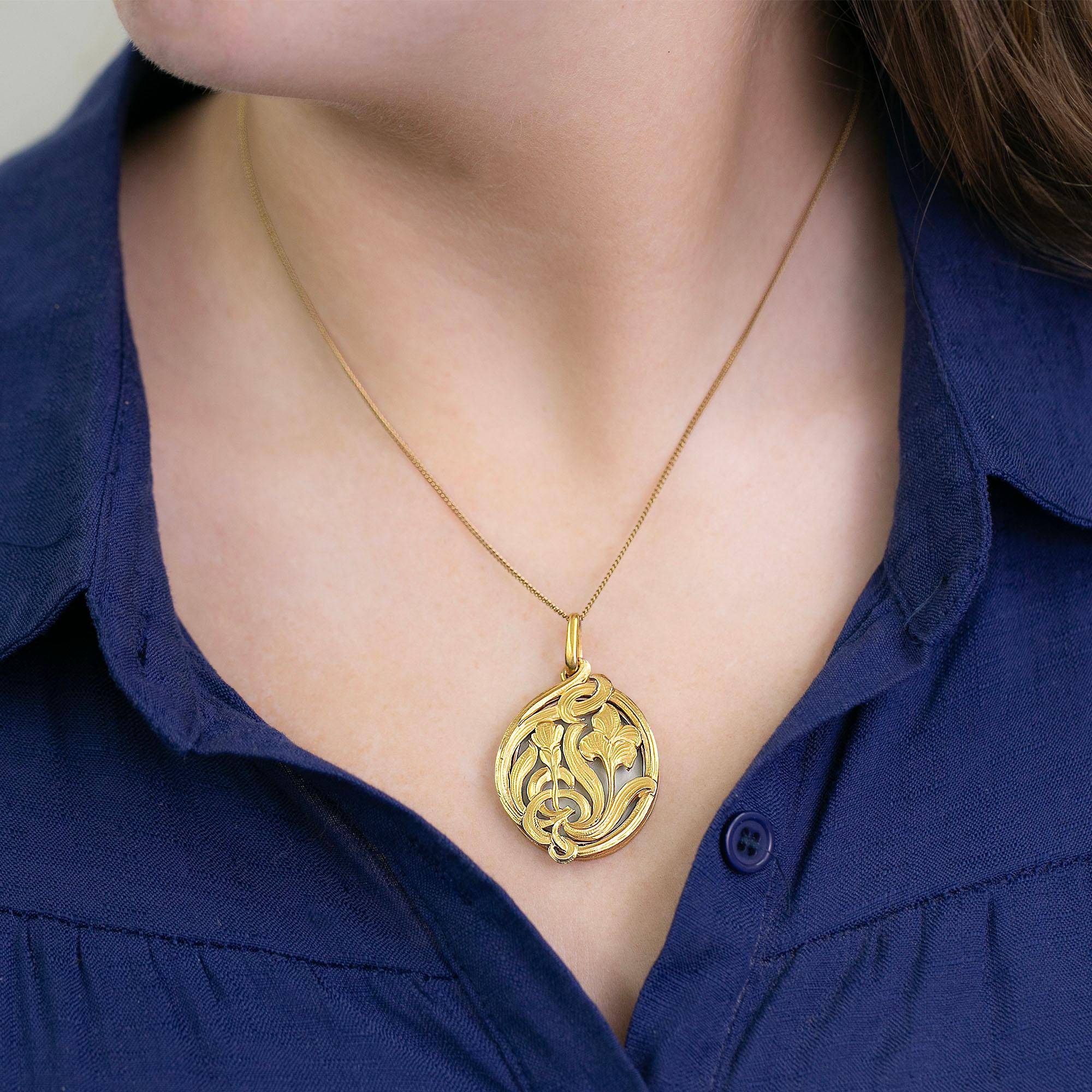 Questo raffinato medaglione ovale a cerniera in stile Art Nouveau di produzione francese è realizzato in oro giallo 18 carati. Caratterizzato da una parte anteriore aperta e traforata con un bellissimo tema floreale intrecciato. All'interno c'è un