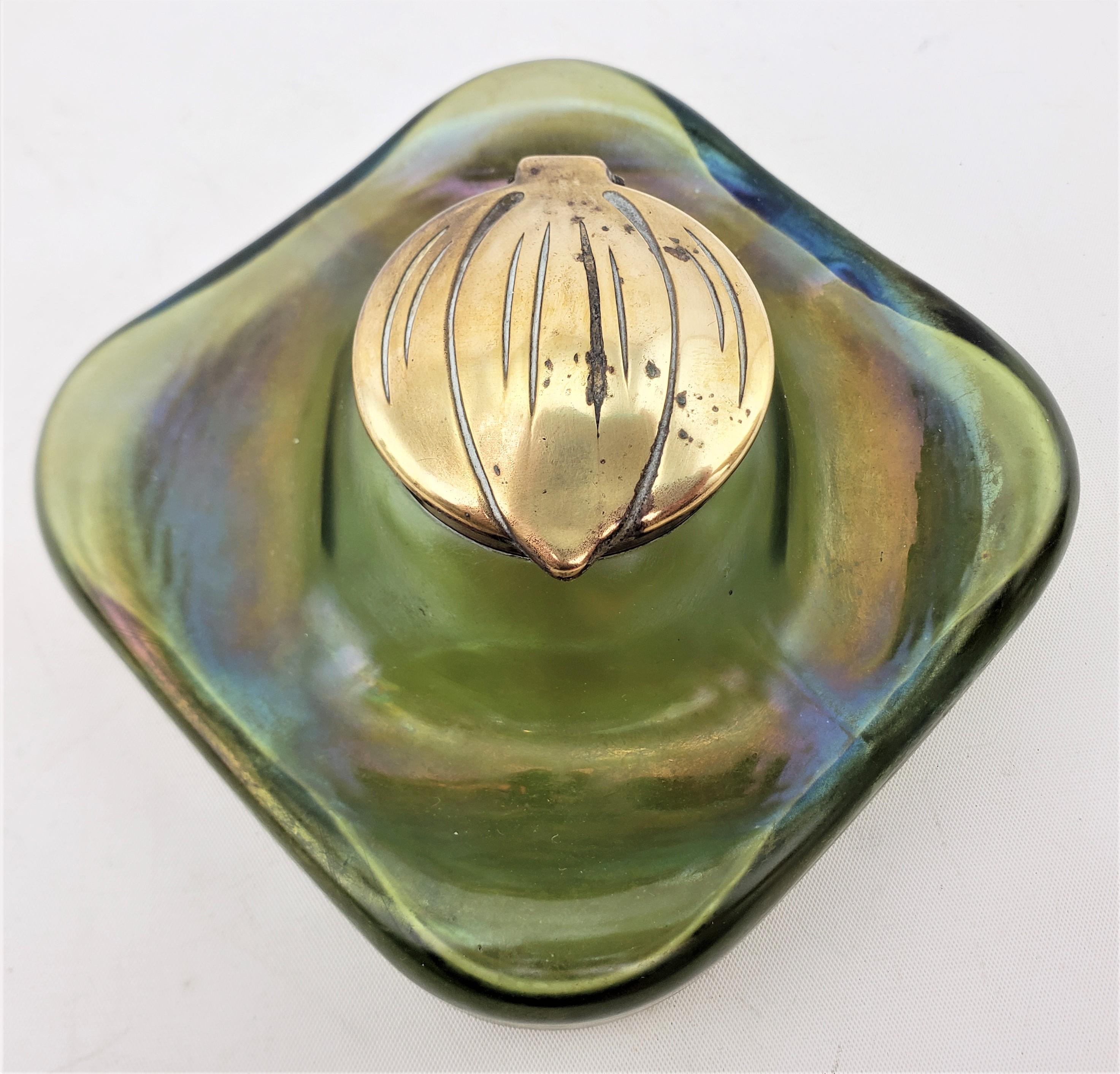 This antique art glass inkwell is unsigned, but presumed to have originated from Austria and date to approximately 1900 and done in the period Art Nouveau style. The body of the inkwell is done in a deep green glass with a strong iridescence and a