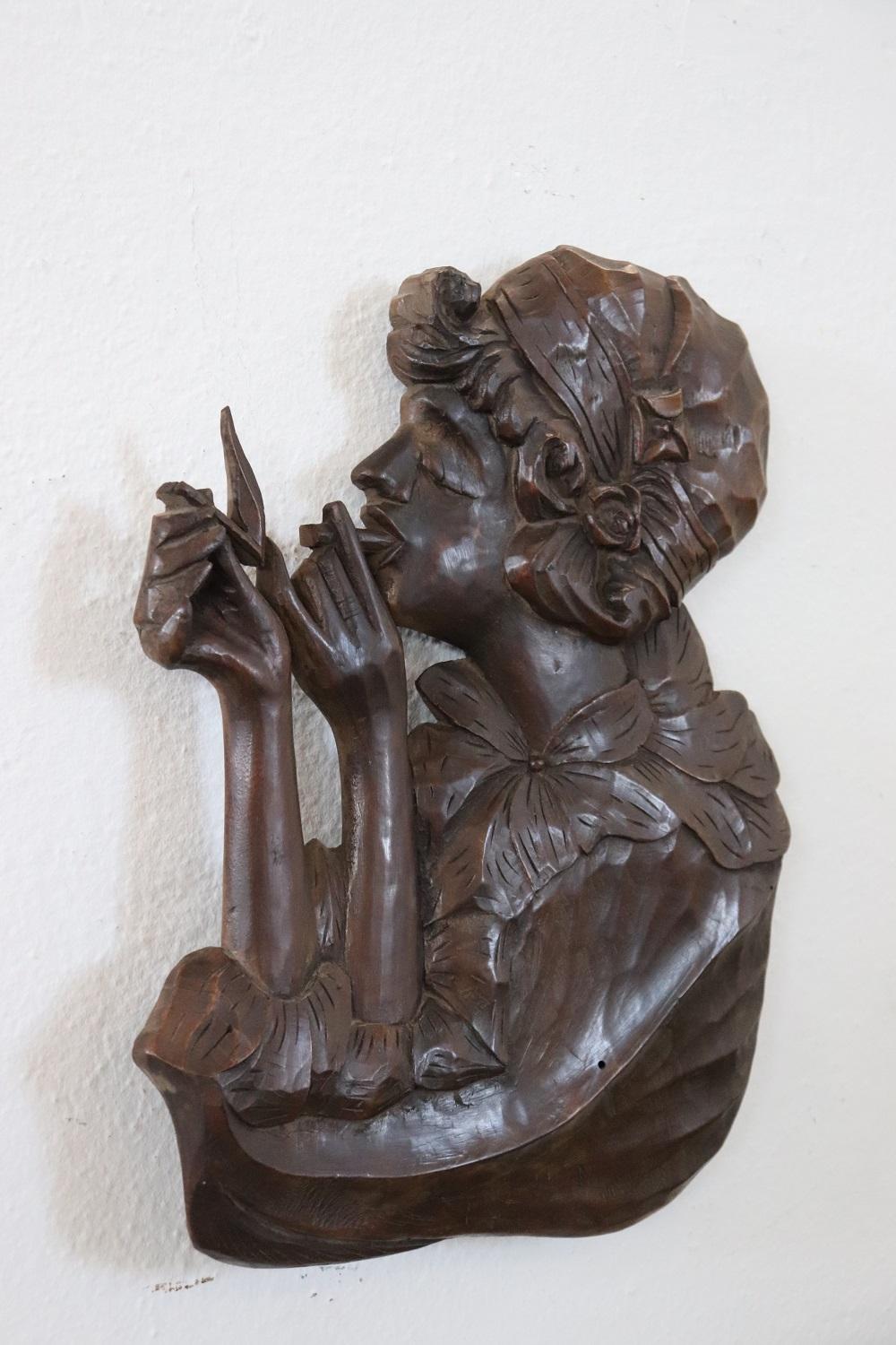 Refined low relief sculpture from the Art Nouveau period in walnut wood. A woman elegantly dressed in the fashion of the Art Nouveau era lighting a cigarette.
 