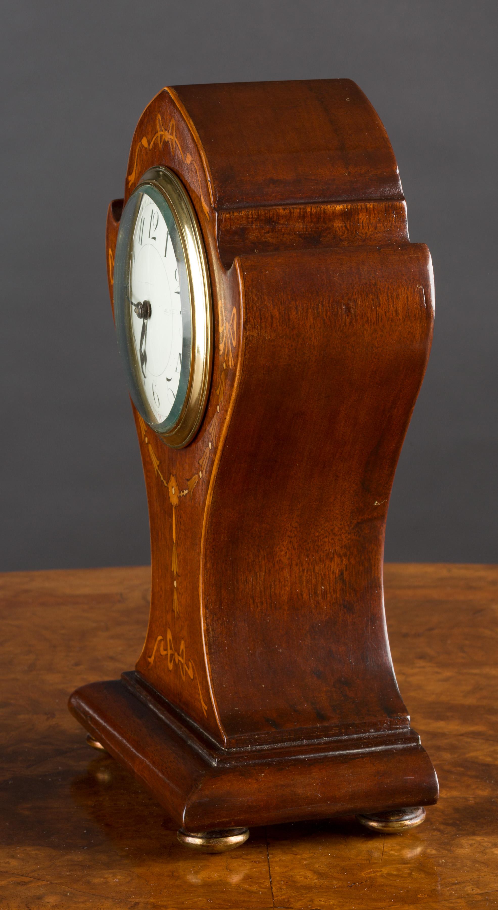 Art Nouveau mahogany Balloon clock with satinwood inlay and standing on brass ball feet. 

Enamel dial with Arabic numerals and original hands.

 Eight day French movement with platform escapement, circa 1910.