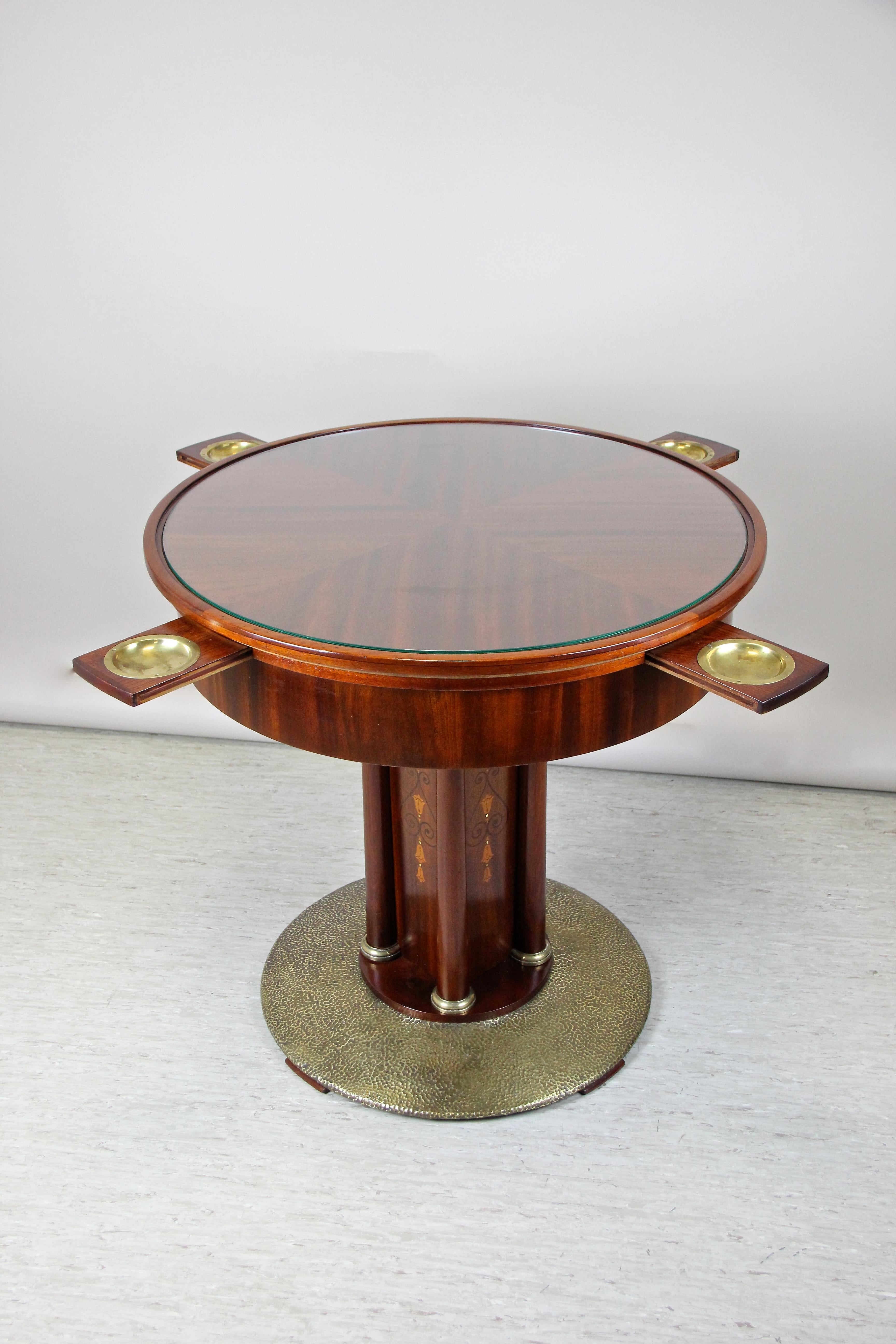 Remarkable Art Nouveau mahogany gaming table out of Vienna/ Austria from the early 20th century circa 1910. The round tabletop, covered by a protecting glass plate, sits on a quadratic column adorned by elaborately fruitwood inlay works on all four