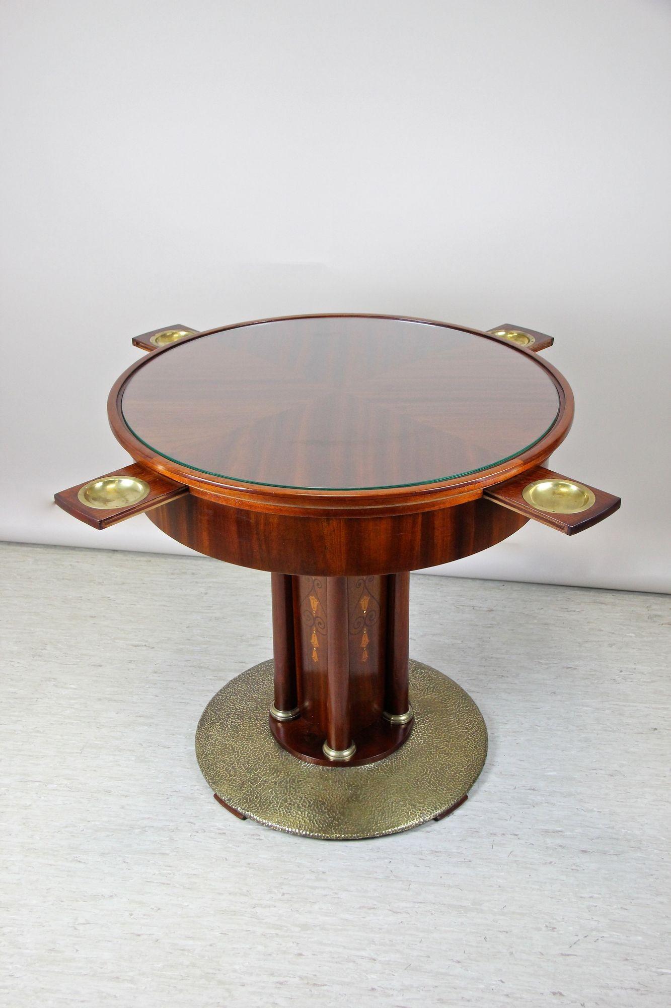 Remarkable Art Nouveau mahogany gaming table out of Vienna/ Austria from the early 20th century circa 1910. The round tabletop, covered by a protecting glass plate, sits on a square column adorned by elaborately fruitwood inlay works on all four