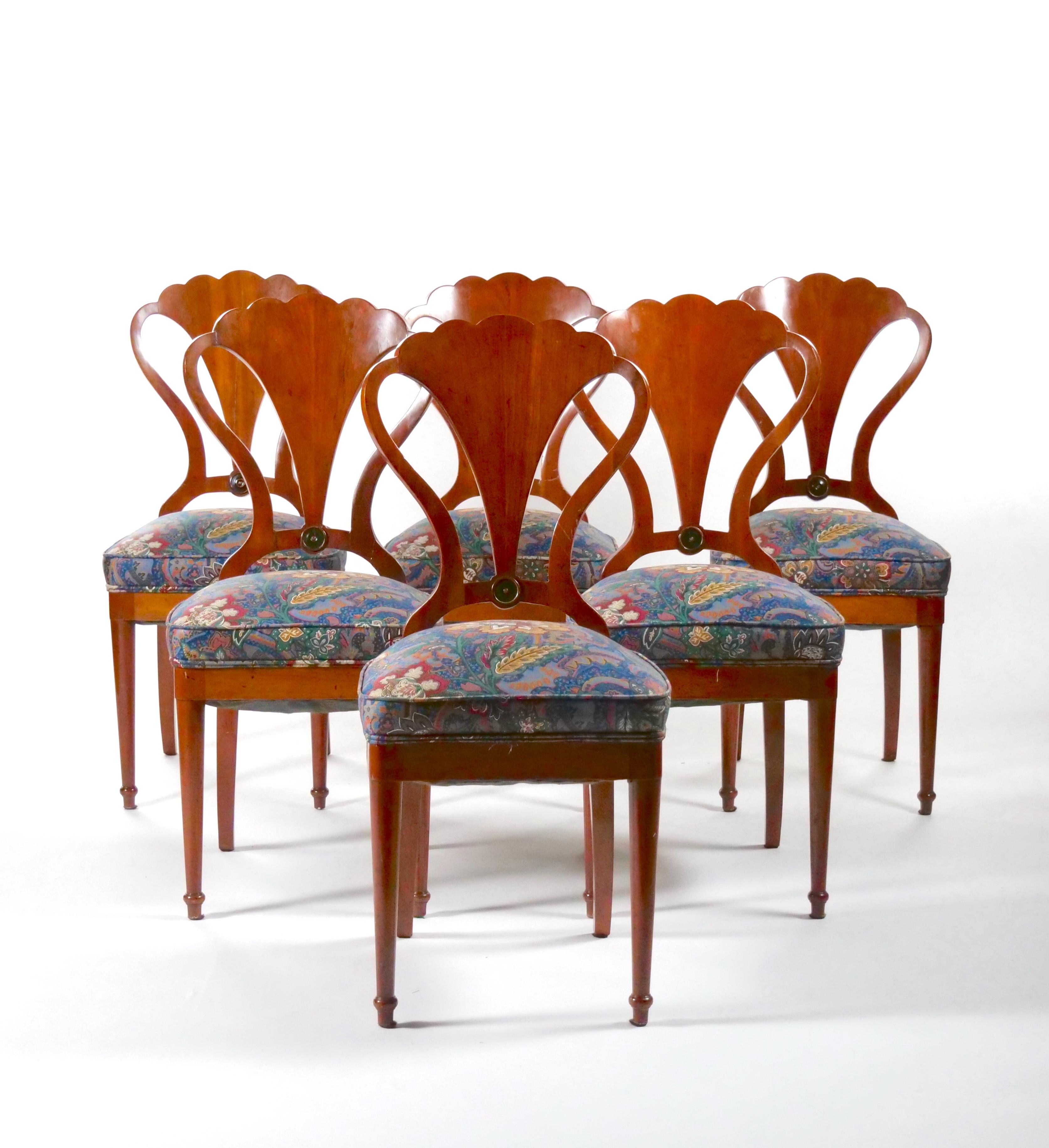 Beautiful Art Nouveau / Art Deco style mahogany wood frame and back set of six dining chairs. The chair features an elaborate hand card mahogany wood shield shaped backs resting on four tapered legs. Each one is upholstered in a cotton blend floral