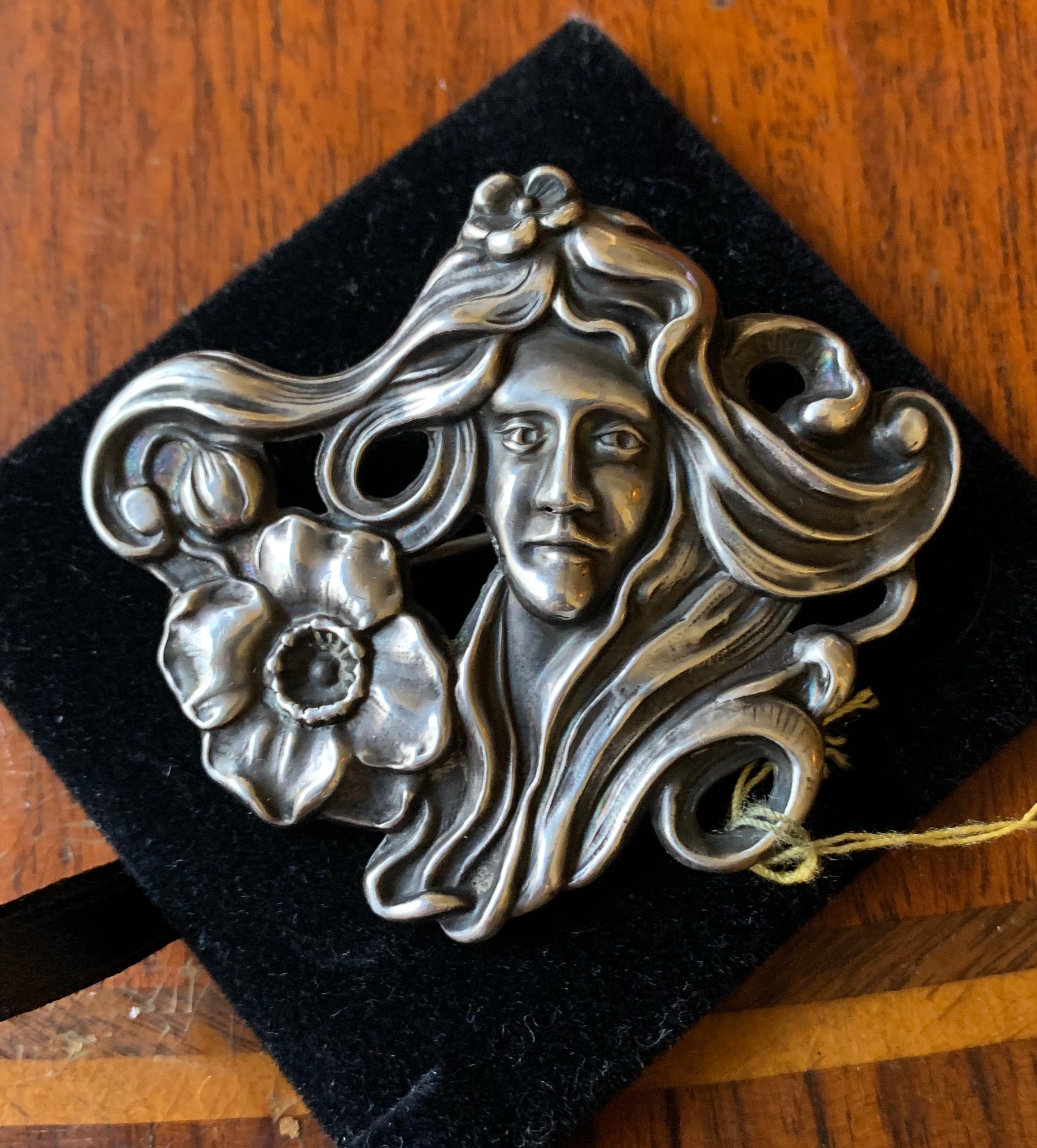 This is a stunning Sterling Silver Art Nouveau Brooch in the form of a Maiden Woman with extraordinary flowing hair encircling her face adorned with gorgeous flowers and buds.  The brooch dates to the Belle Epoque - Art Nouveau period, circa 1880 -