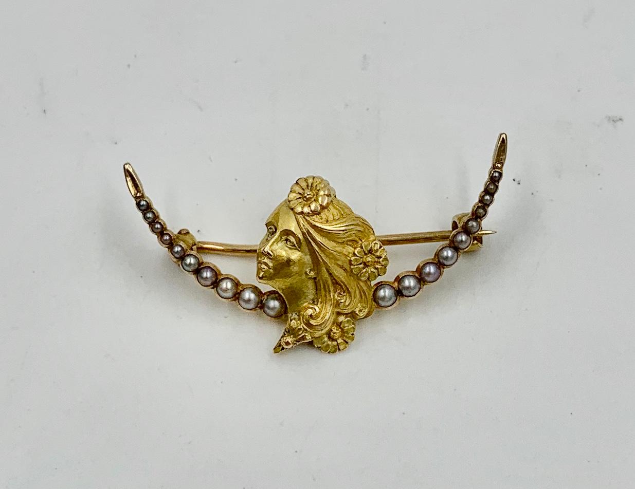 Eine atemberaubende Brosche in Form einer Jungfrau mit Blumen im Haar, besetzt mit Perlen in einem Mondsichelmotiv.  Die Frauenbrosche stammt aus der Zeit der Belle Epoque und des Jugendstils (ca. 1880 - 1915).  Die Brosche ist aus 14 Karat Gold. 