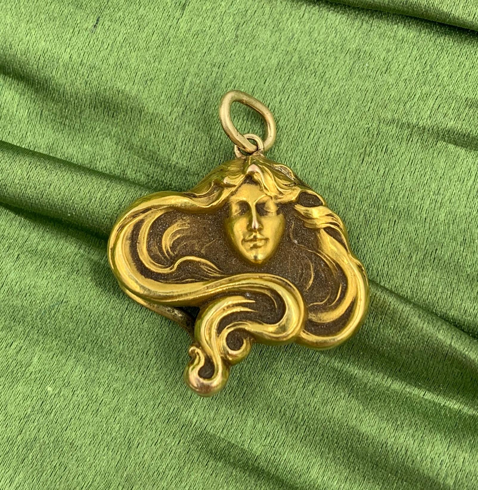 Ein atemberaubender Anhänger in Form einer Jungfrau mit außergewöhnlichem:: fließendem Haar:: das ihr Gesicht umgibt.  Der Lavalier-Anhänger Frau stammt aus der Belle Epoque - Jugendstilzeit:: ca. 1880 - 1915.  Die Brosche ist aus 14 Karat Gold. 