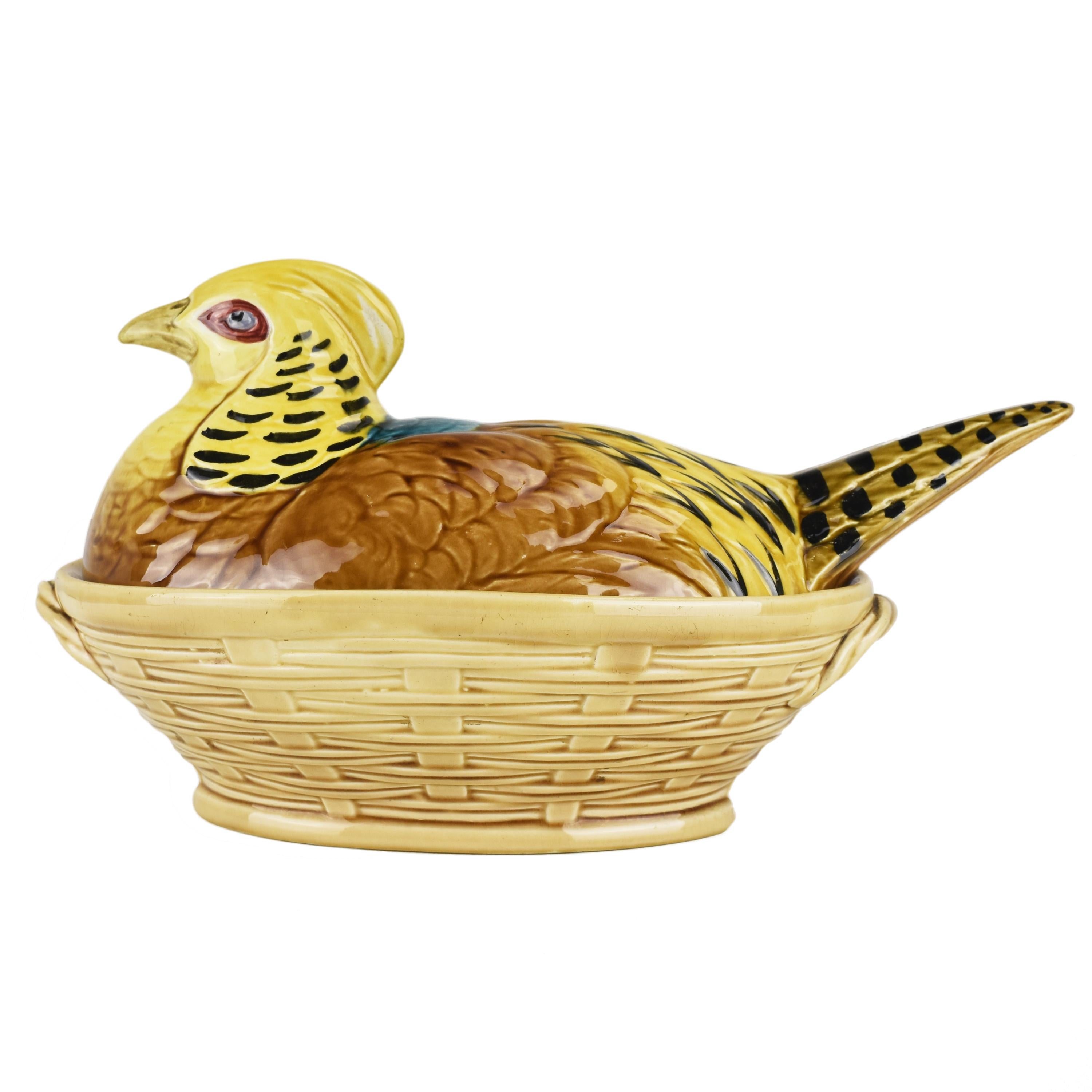 A hand-painted majolica lidded jar / box or tureen in the shape of a pheasant hen sitting on a basket, made by Sarreguemines around 1900. This beautiful and antique piece is made of hand-painted majolica, a type of earthenware known for its vibrant