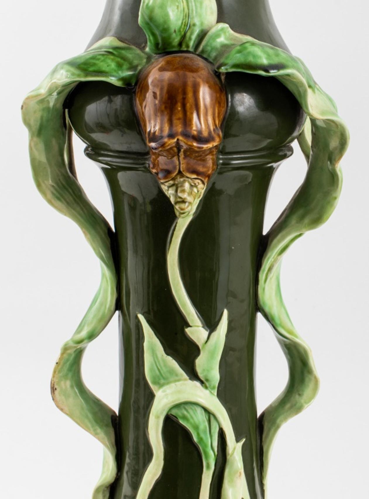 Art Nouveau majolica dark green enamel-glazed ceramic plant stand with light green leaves in high relief and two brown floral handles, the underside impressed 