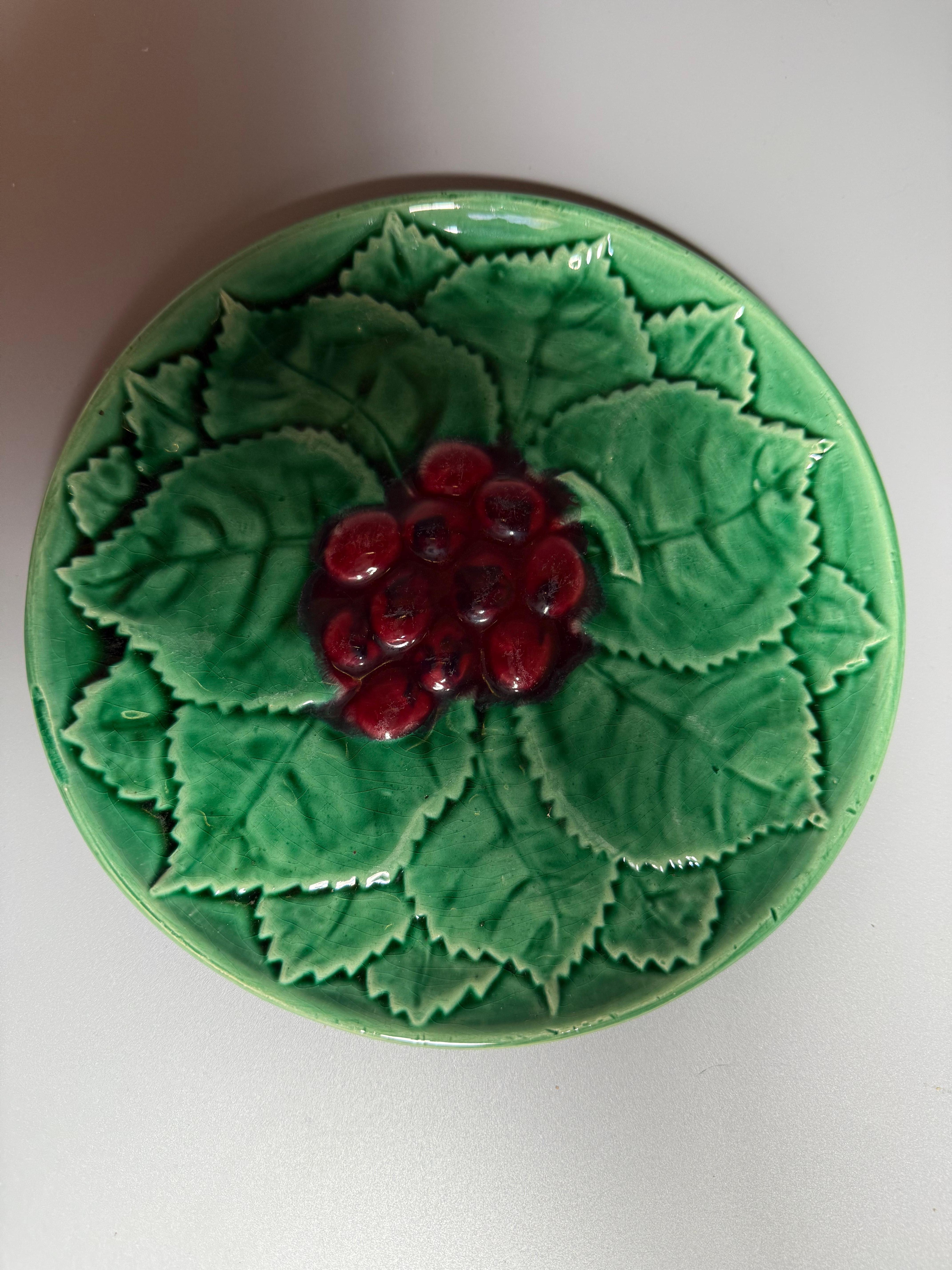  L'assiette présentée sur l'image semble être une assiette en céramique d'époque avec un motif en relief représentant des feuilles et des baies, caractéristique de la majolique ou de la Barbotine. 
L'Atelier de Cerenne (souvent mal orthographié