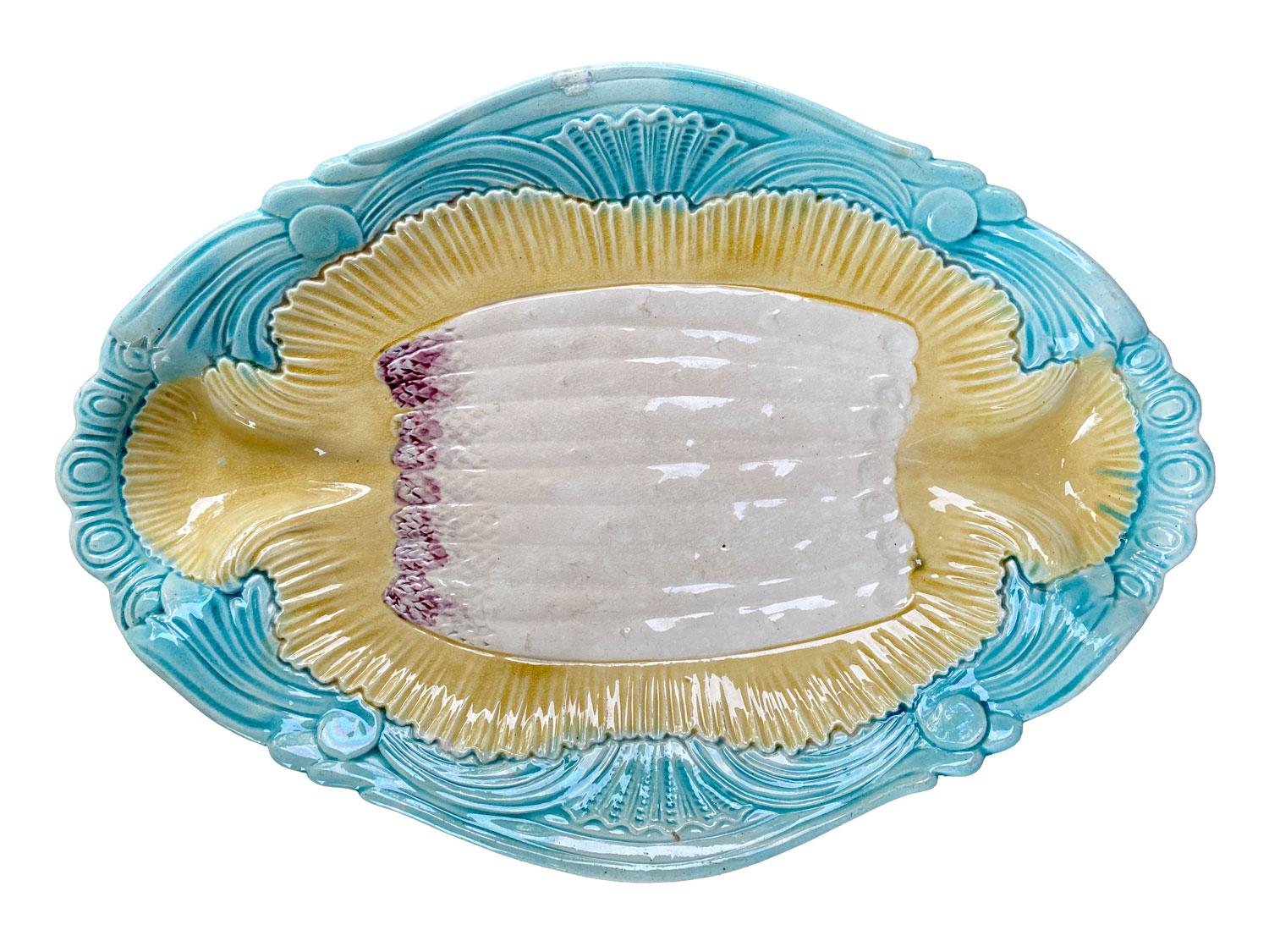 Cette assiette en majolique peinte à la main en forme d'asperge a été fabriquée en France au XIXe siècle. Décoré au centre d'asperges en Barbotine - slip avec motif de coquille jaune sur la lèvre et bordure bleue de style art nouveau. Marqué 5 au
