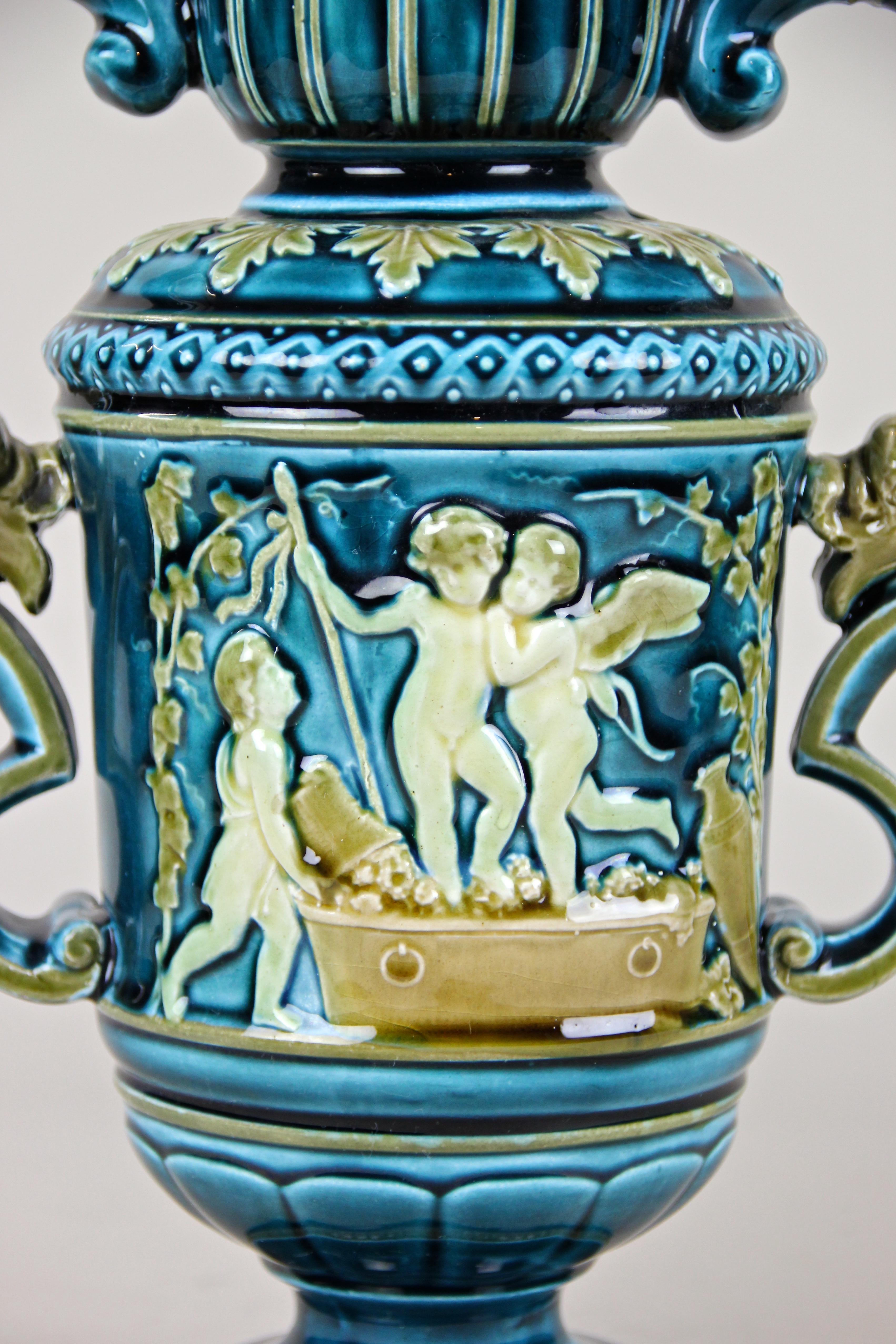 Decorative Art Nouveau Majolica vase made by the famous manufacture Schuetz Blansko, circa 1900. The early 20th century Amphora vase with an amazing design impresses with beautiful depictions of puttis, artfully shaped handles and a fantastic