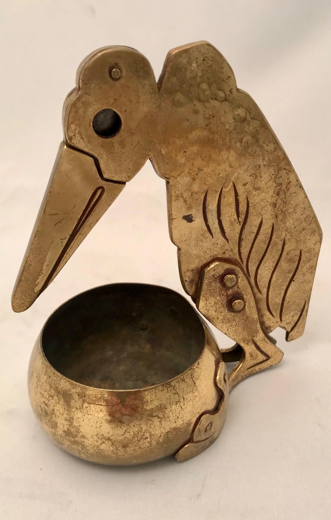 Figural cigar cutter with ash tray in the shape of a maribou, leaning over a bowl. The bird's-eye is the opening for the cigar and the beak is the knife. the stub falls into the bowl  brass, hand crafted around 1910. 