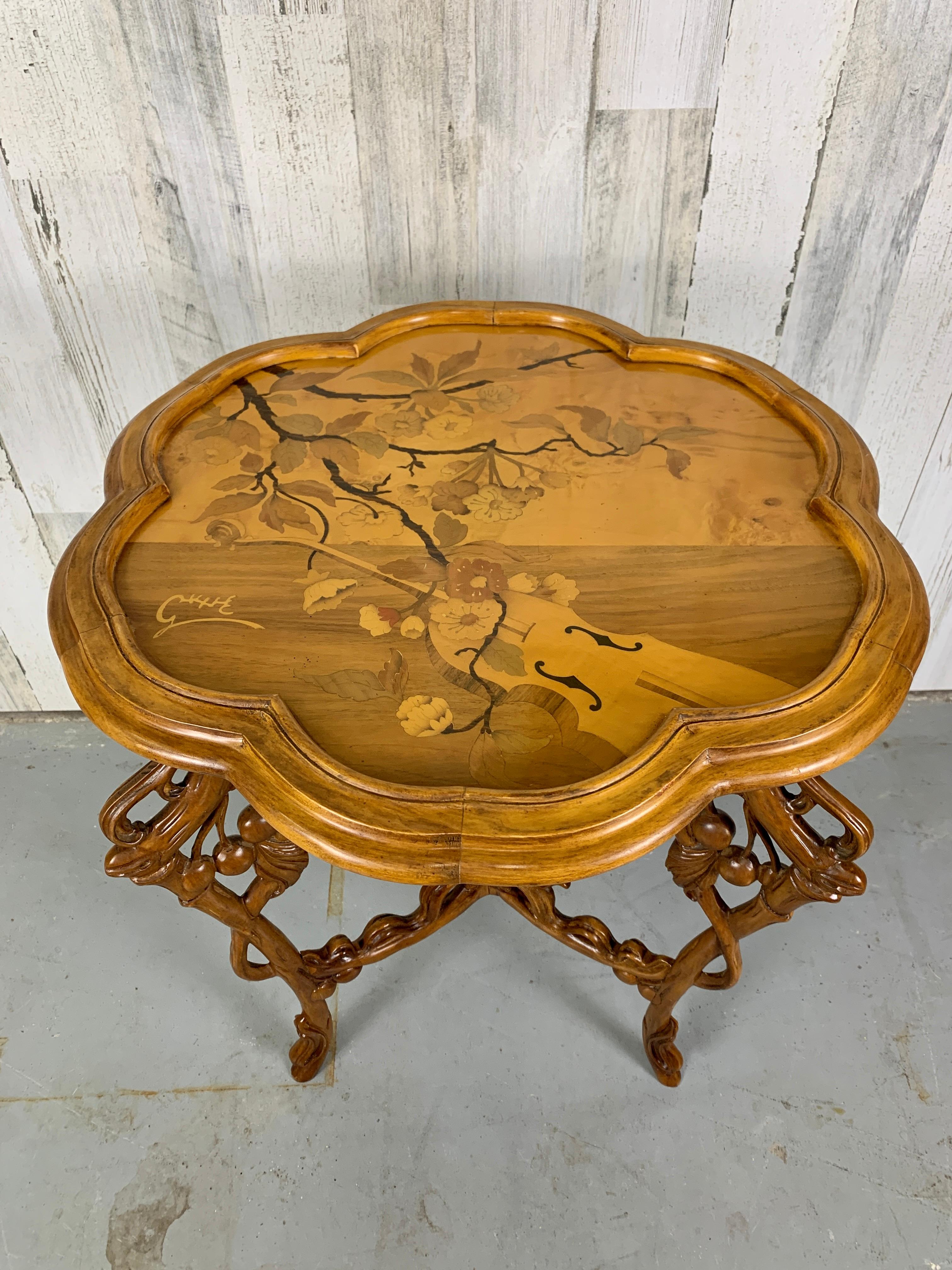 Art Nouveau table in carved walnut with floral and musical motive marquetry.