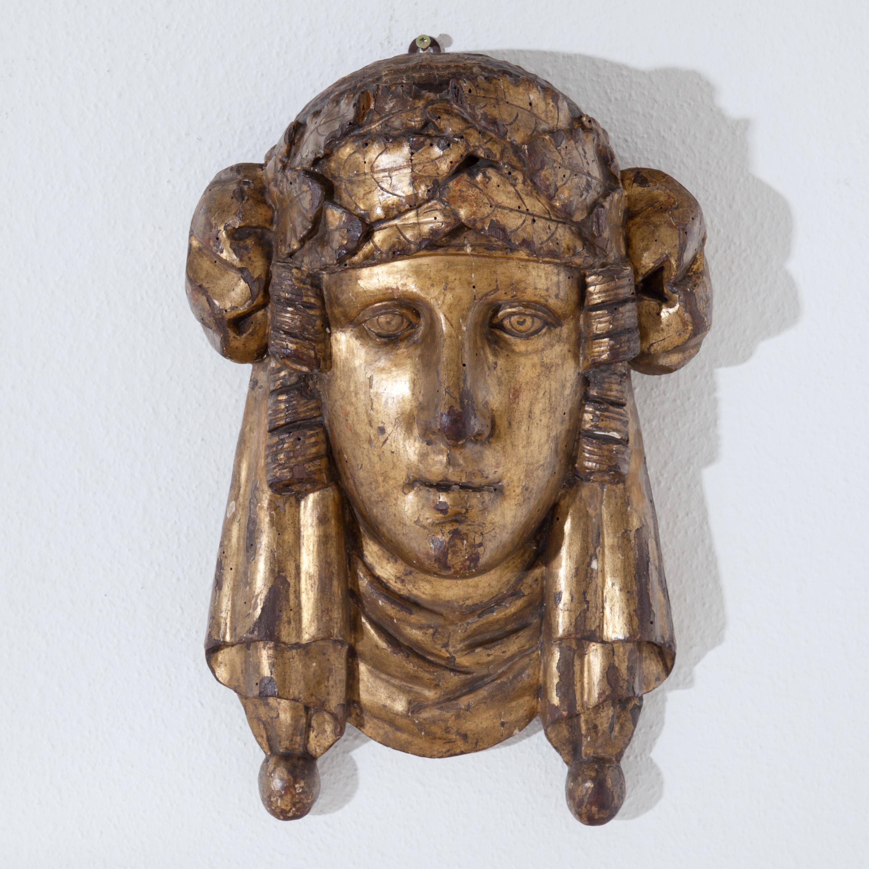 Mascaron of a young lady with Art Nouveau head-dress, carved in wood and gilded.