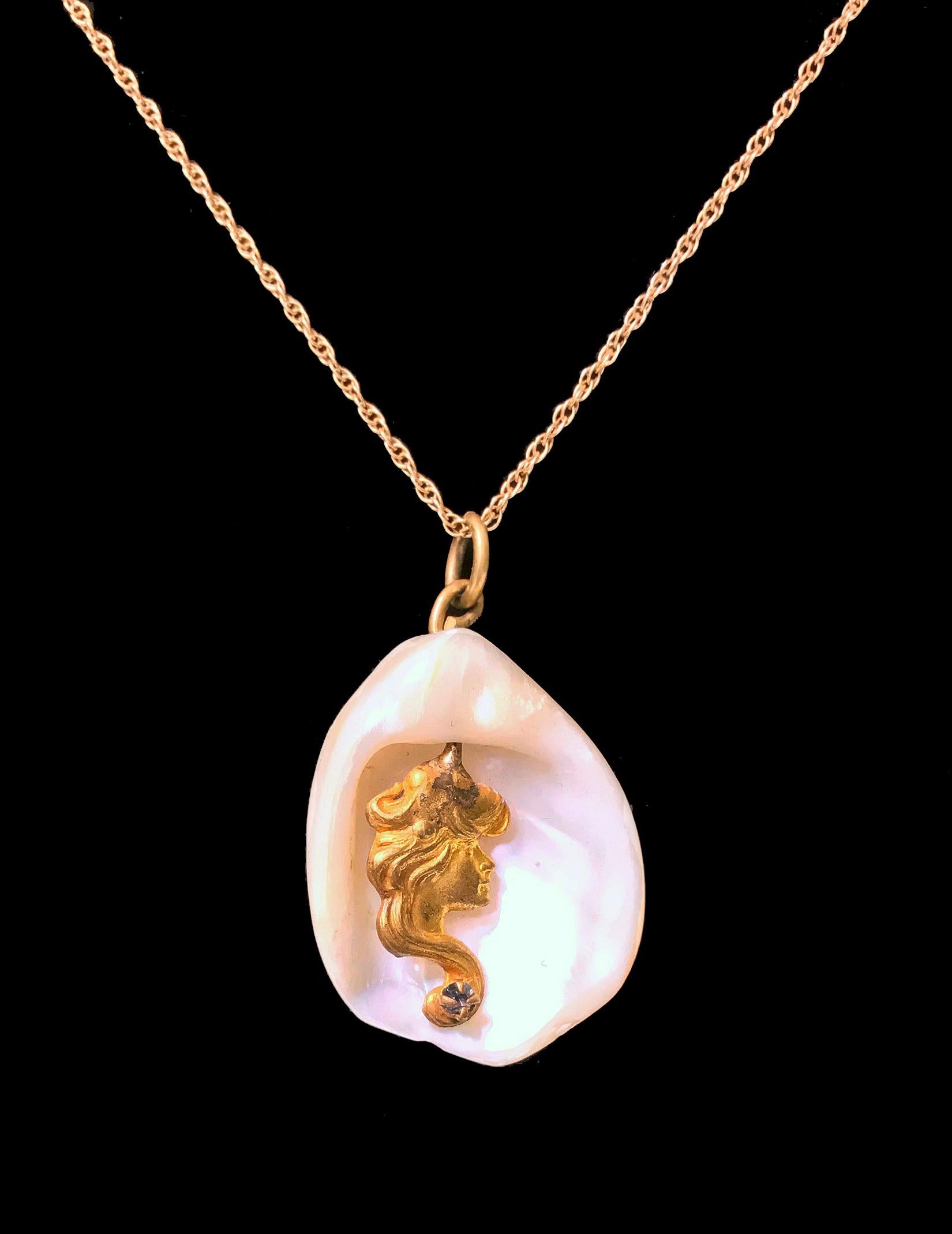 Art Nouveau Lady Mermaid in shell stone, C.1920. The female gilt profile set with small faceted white stone at base, later 14K (stamped) gold chain attached. Drop measures approximately 1.50 x 1.00 inches. Chain: 18.50 inches. Total Item Weight: