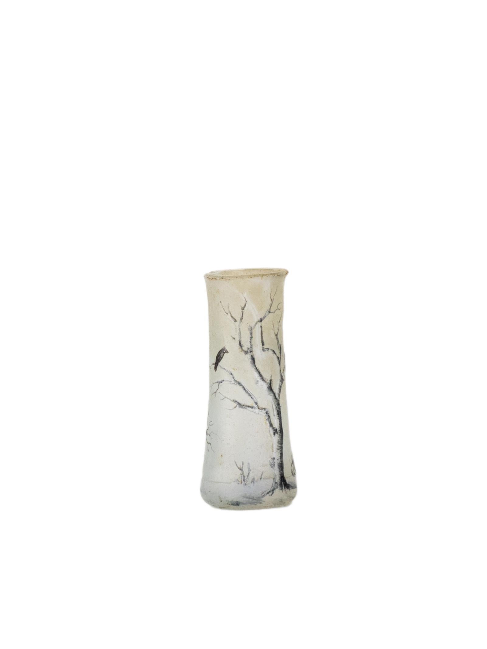 A signed Daum miniature vase from the early 1900s, featuring a delicate winter landscape in acid-etched and polychrome enamel over multilayered glass. 
At just 1.58 inches tall, this tiny treasure captures the poetic stillness of a snow-covered tree