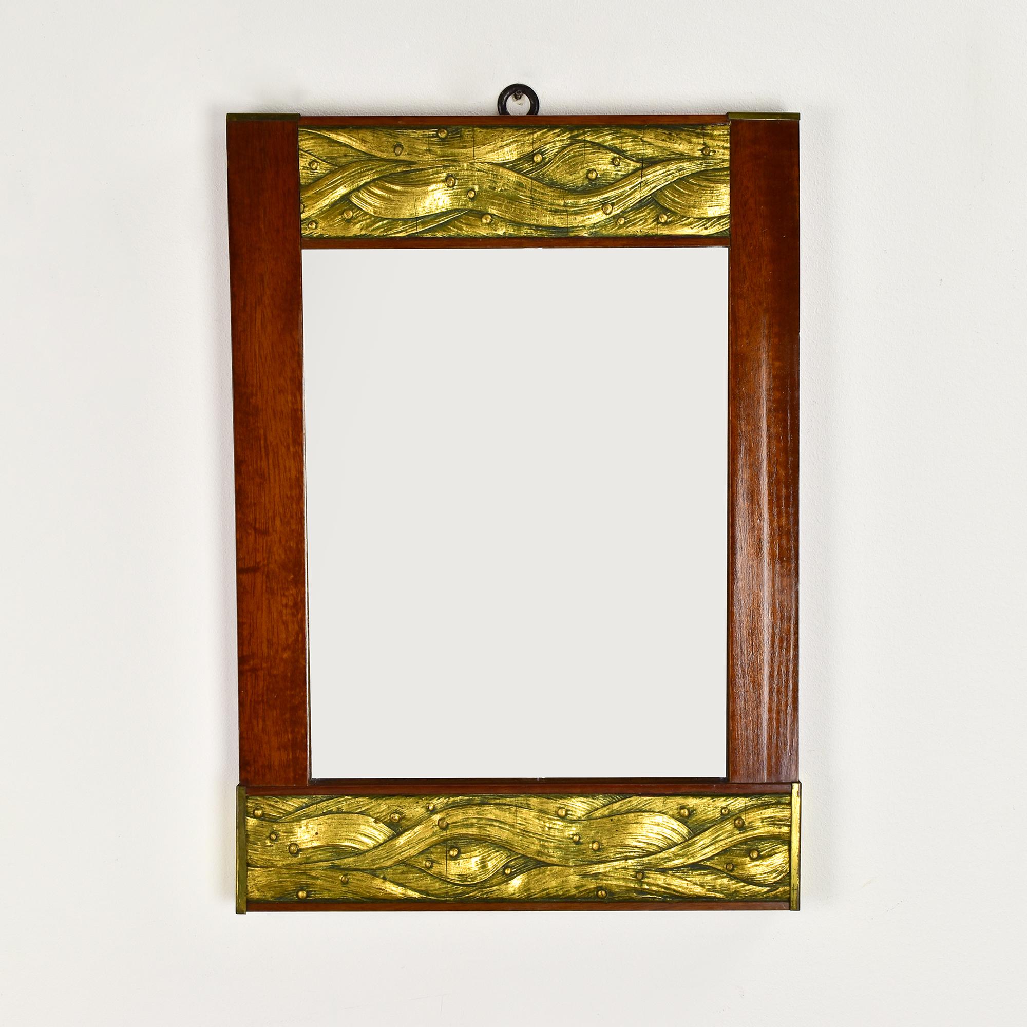 Eleganter Jugendstil-Wandspiegel aus der Zeit um 1900, mit einem fein gearbeiteten Rahmen aus massivem Mahagoni. Das reiche rötlich-braune Holz wird durch vergoldete Stuckplatten (Gips) an der Ober- und Unterseite und Endplatten aus Messing oder
