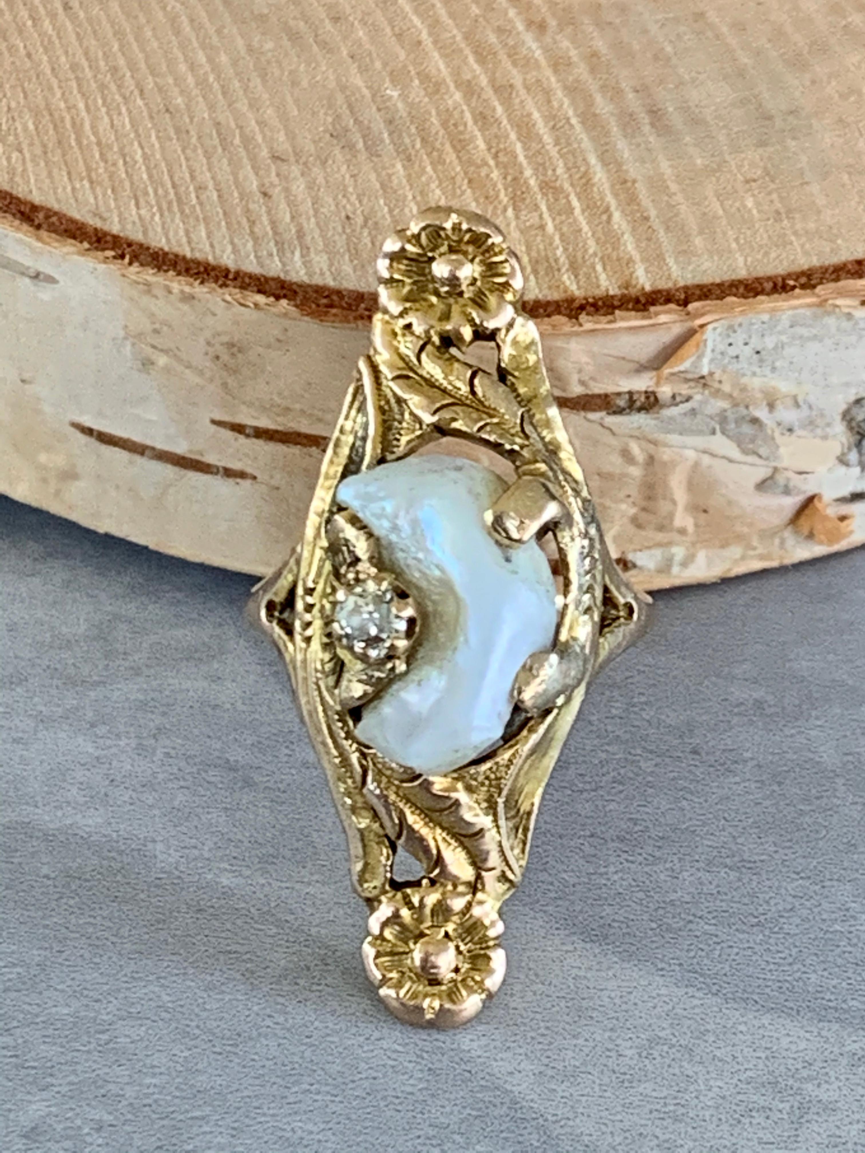 This unique Art Nouveau Mississippi River Pearl ring features two bezel set 2.5mm European cut Diamonds. The total weight is .15ctw; grades Si(I)-H.
The Pearl has a unique shape which looks like a beautiful crescent moon.
These rings are so lovely