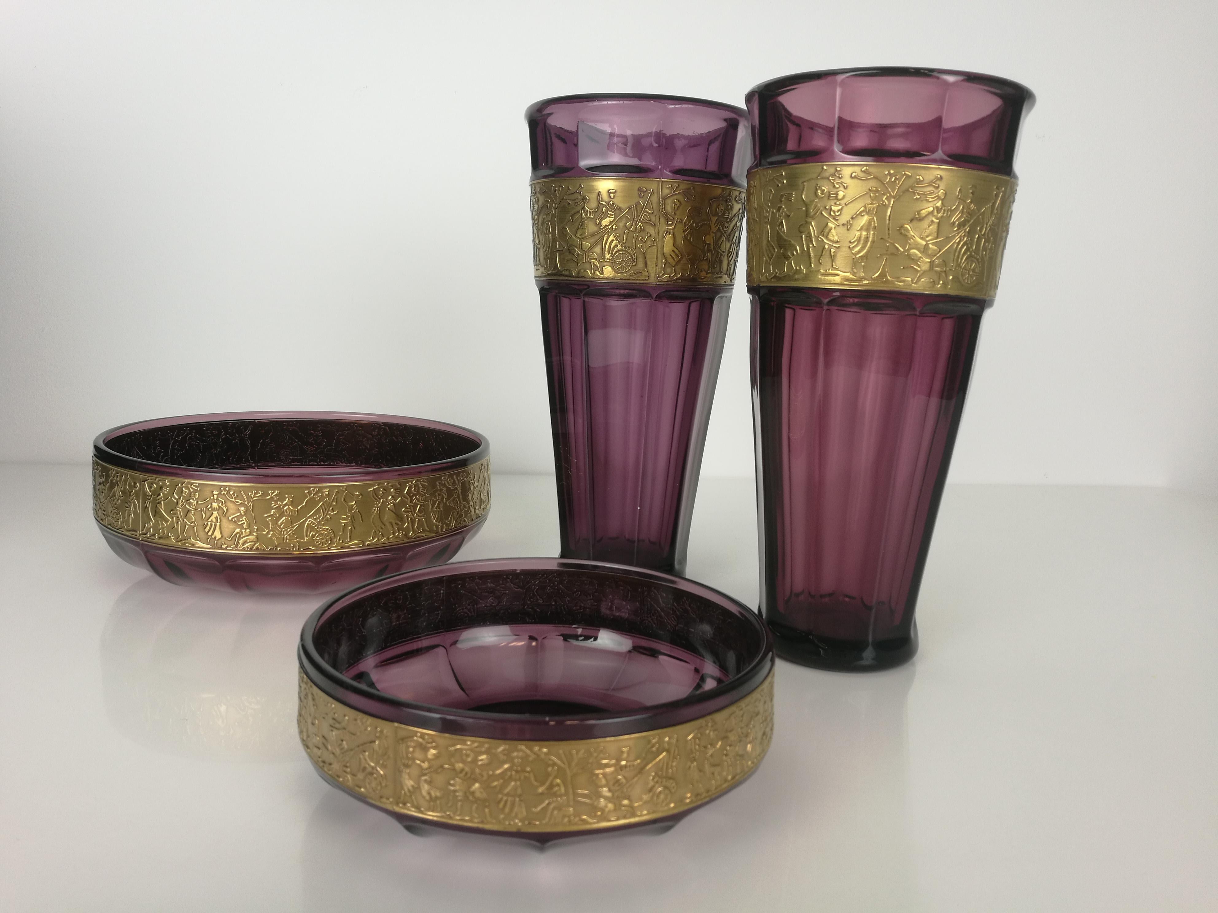 A beautiful Moser amethyst centerpiece set. Two vases and two bowls. Hand blown purple crystal with a wide band around the body, decorated with a cameo cut scene with antique roman chariots, embellished with gold.

Maker: Karlsbader Kristallfabrik