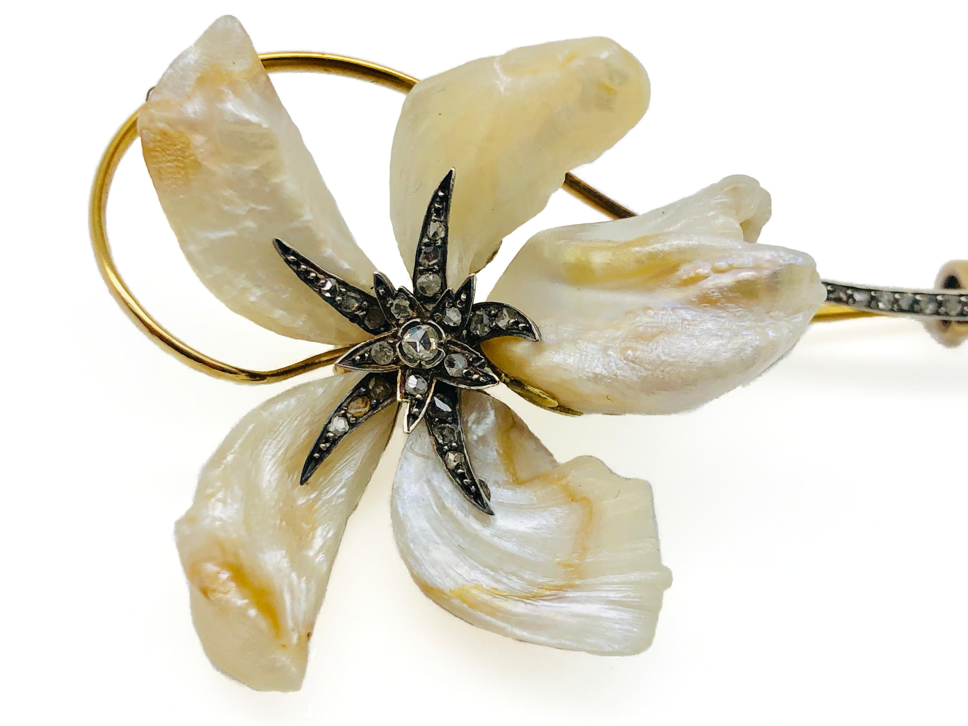 Beautifully designed Art Nouveau flower brooch. Five natural baroque pearls have been transformed into flower petals and mounted on gold. The center of the flower is made out of silver and set with old cut diamonds. The golden flower stem terminates