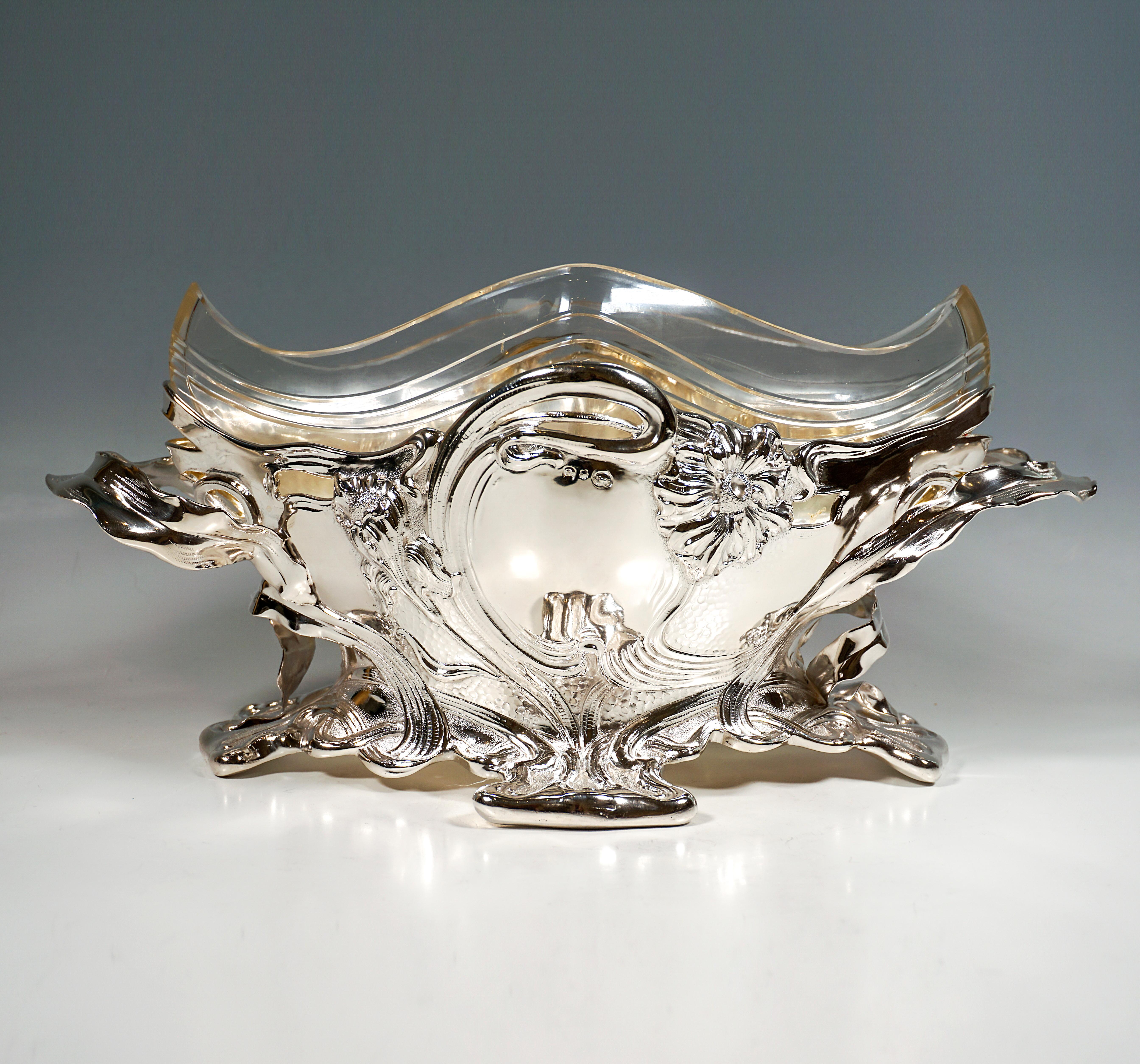 Festive solid silver vessel in the form of a navette-shaped bowl with a lobed, projecting foot resting on four points of contact, large rocaille-shaped panels on the front and back framed by floral relief decoration in the form of intertwined