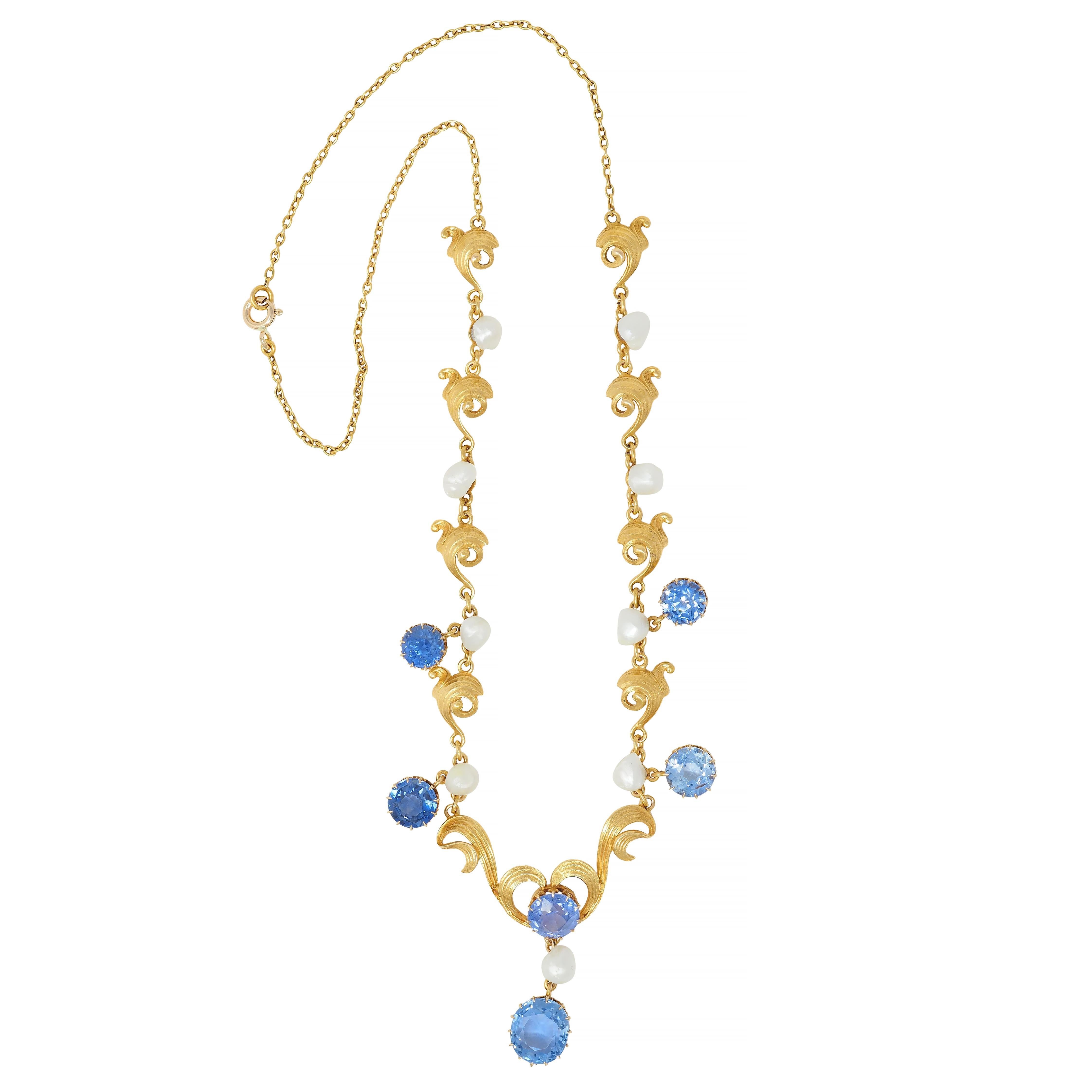 Designed as a station style lavaliere necklace with cable link chain and dimensional scroll motif links
With engraved linear texture throughout - centering a sweeping heart motif suspending drop
Featuring an oval cut sapphire weighing 3.22 carats -