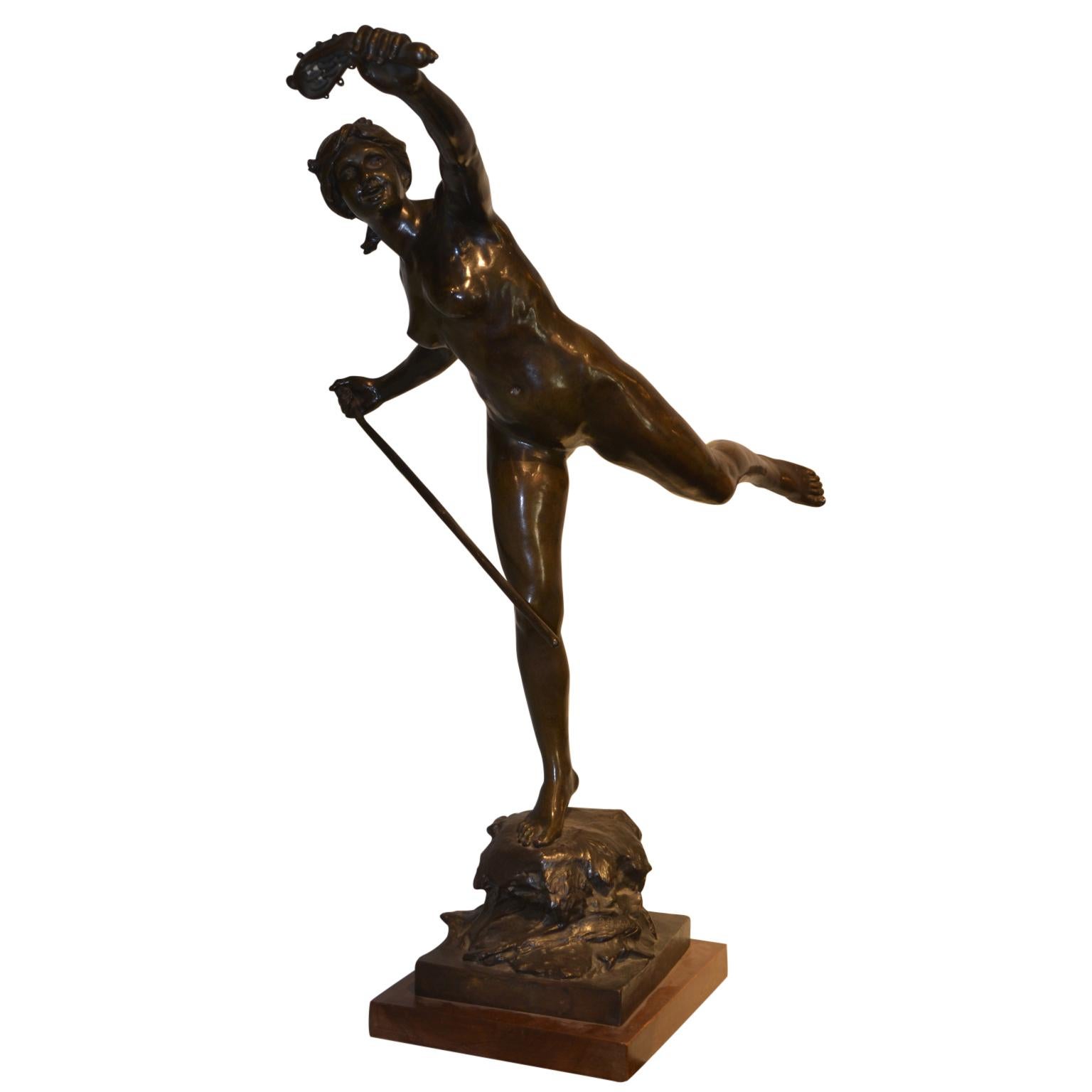 A beautifully cast bronze having a dark brown patina of a young woman almost leaping in the air, her right foot standing on a ‘rocky outcrop’, her right arm holding a stick of some kind, her left leg outstretched behind and her left arm holding what