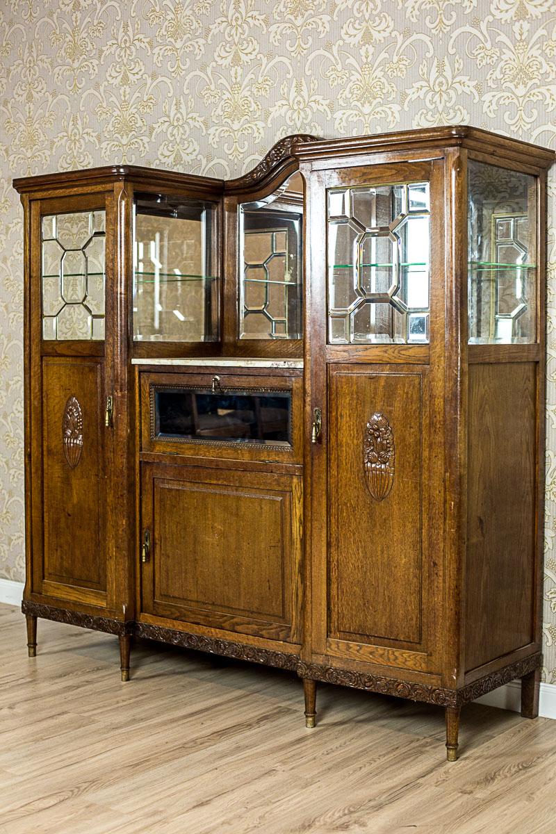 We present you this piece of furniture, circa early 20th century, made entirely of solid oakwood.
This cupboard is composed of two higher cabinets and a smaller one, in the middle, with a wall with a mirror.
The outer cabinets, in the upper