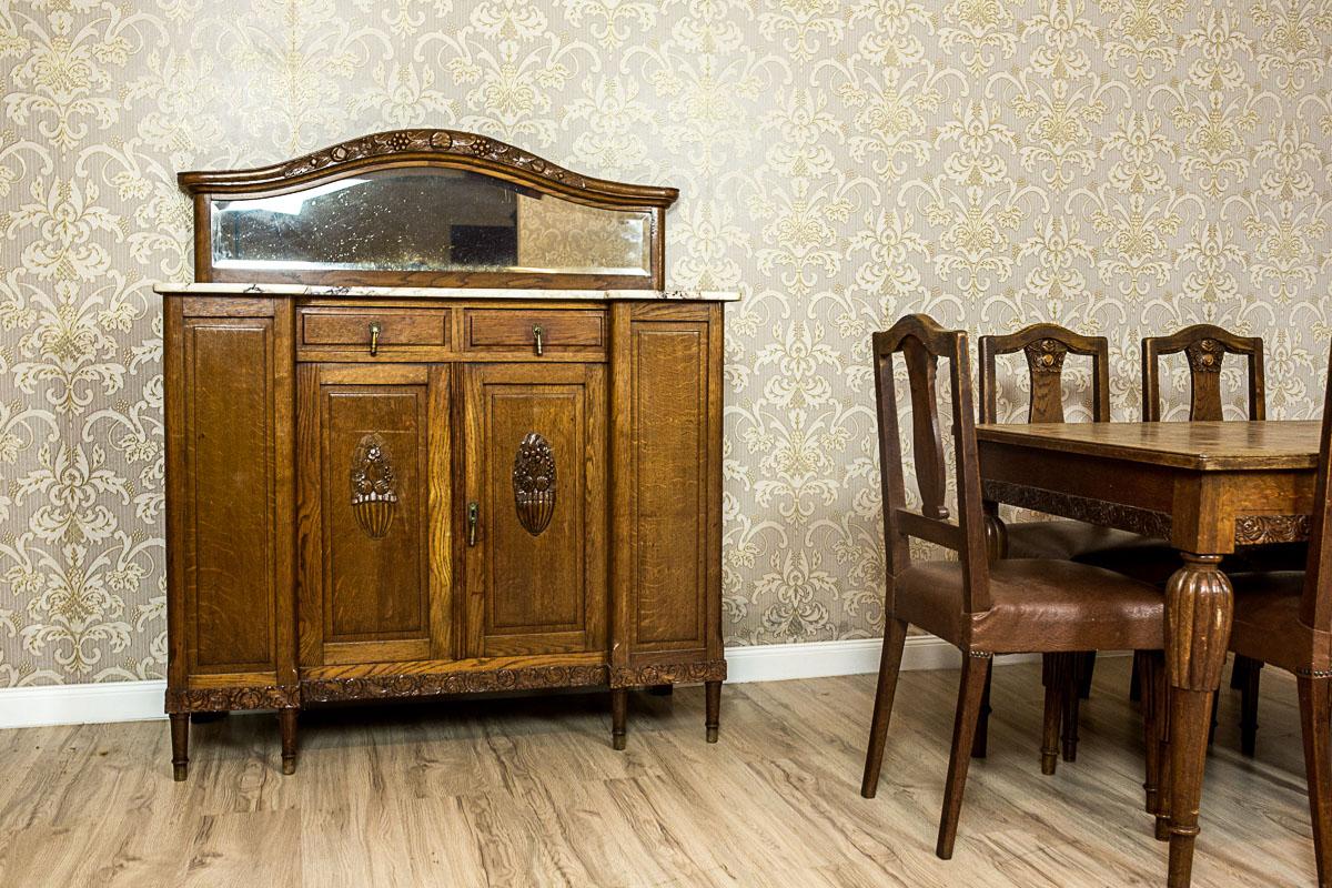 We present you this set composed of a big table and six chairs, and a cupboard and a sideboard.
The whole is made of oakwood.
The table and chairs have Windsor legs, which are fluted in the upper section.
The lower section of the apron of the