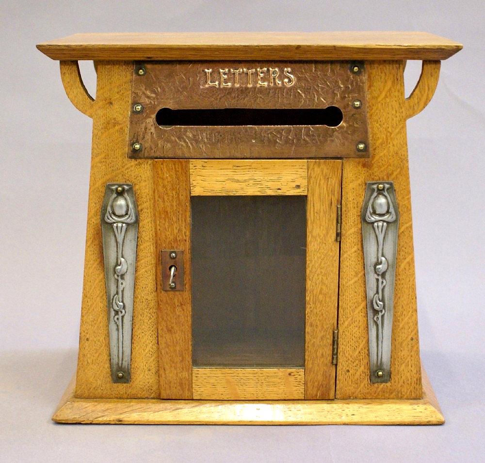 This charming and delightful Art Nouveau free standing oak letter box features design details in pewter, brass and copper. This lovely little piece of history is both rare and an excellent example of the time, complete with the original lock and