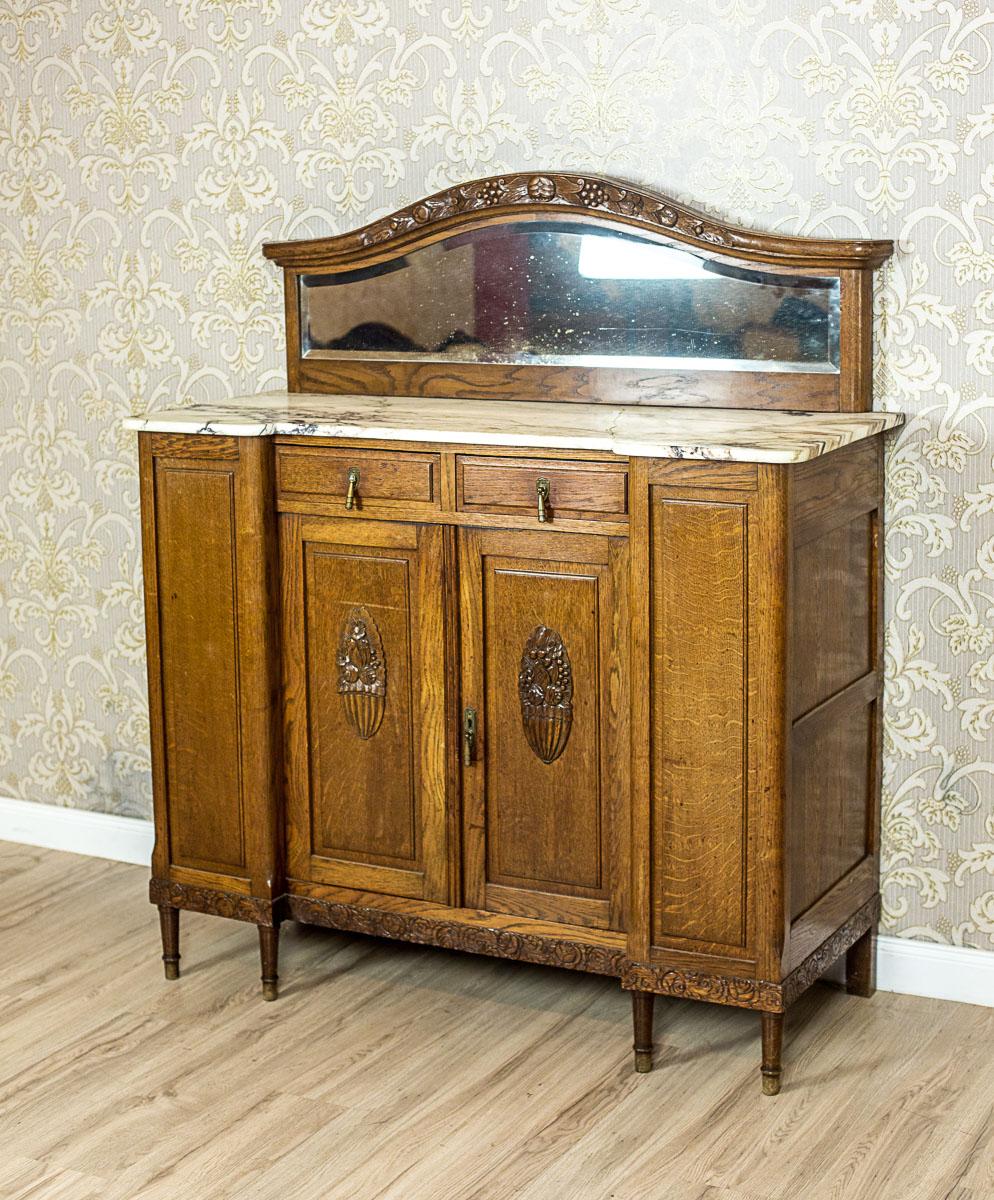 We present you this piece of furniture, circa early 20th century, made entirely of solid oak wood.
The apron is two-door; with extended sides with blank windows.
There are two drawers on the door axis. The whole is topped with a marble