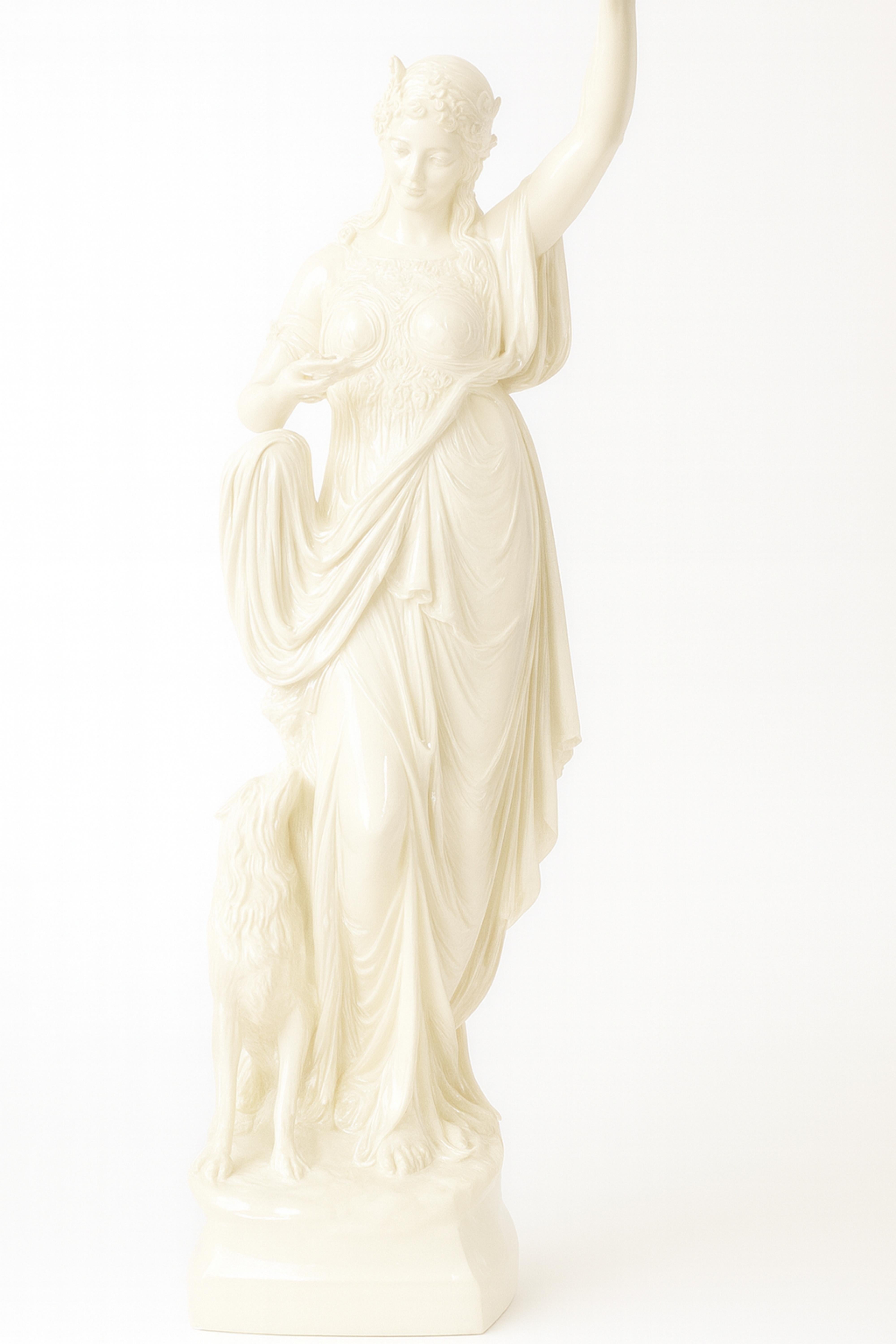 Eine Art Nouveau-Lampe aus weißem Lack, die eine anmutige Frau aus der Belle Époque darstellt, die eine leuchtend gelbe Glasschale hält,
Die Skulptur zeigt eine heitere junge Frau mit fließendem Gewand und Girlandenkranz, die einen Arm in den Himmel