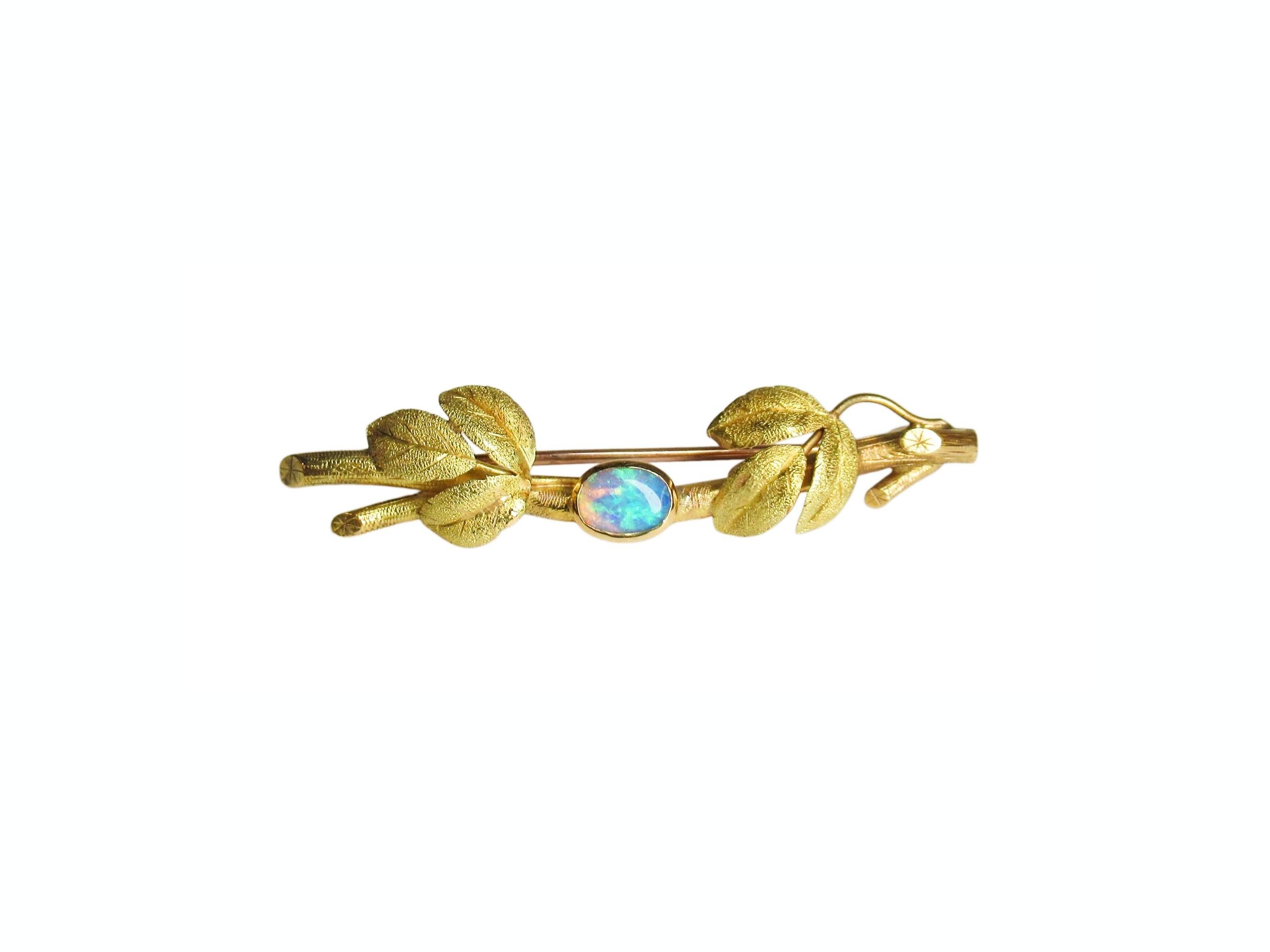 Splendida spilla antica in oro giallo 18k a forma di foglia e ramo con uno splendido opale cabochon. L'opale ha un eccezionale gioco di colori: blu pavone intenso, verde brillante, indaco e pesca a seconda della luce. Il cabochon ovale misura circa