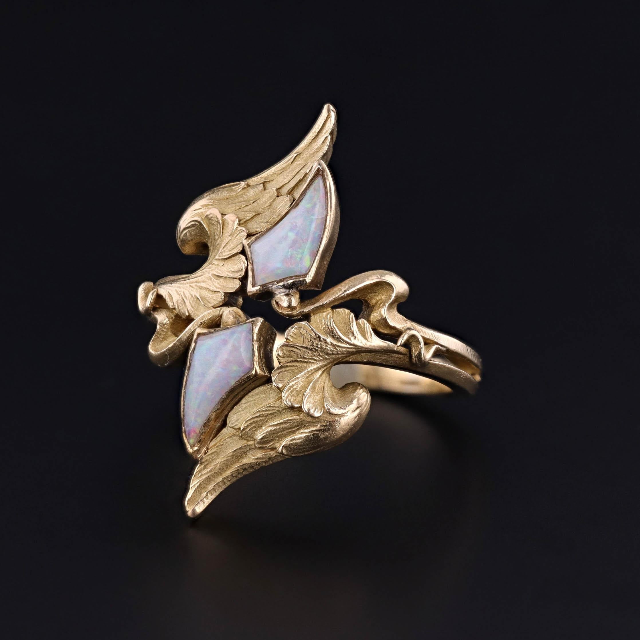 Un antico anello di epoca Art Nouveau in oro 18k con un motivo ad ali e due opali bianchi infuocati. L'anello finemente lavorato (circa 1910) reca marchi di importazione francese sulla parte esterna della fascia.

La faccia dell'anello misura 1,05