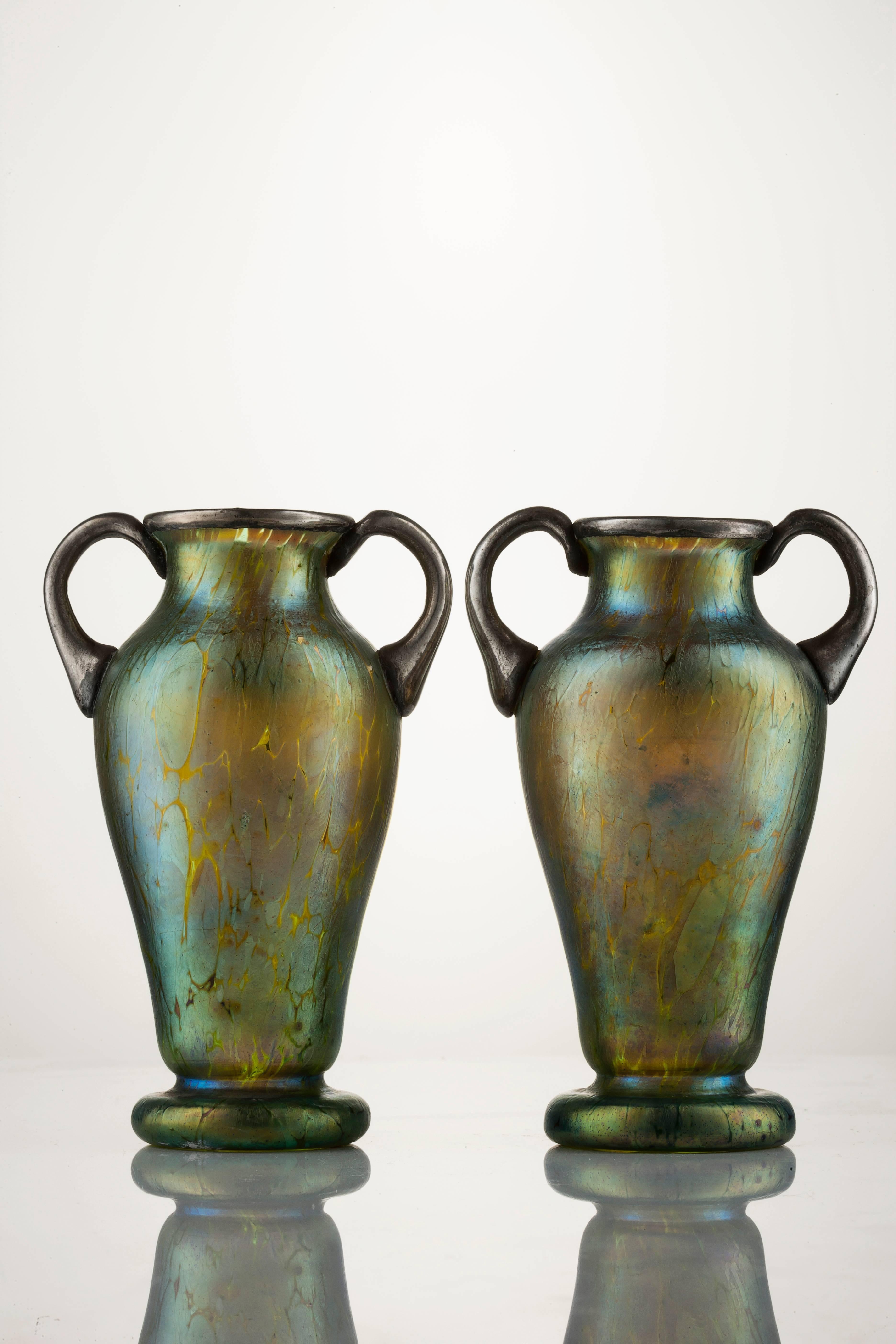 A pair of iridescent glass Amphora vases with a silver Art Nouveau organic floral decoration applied to the body and neck of the vases. This is a fine example of Johann Loetz from 1900.
     