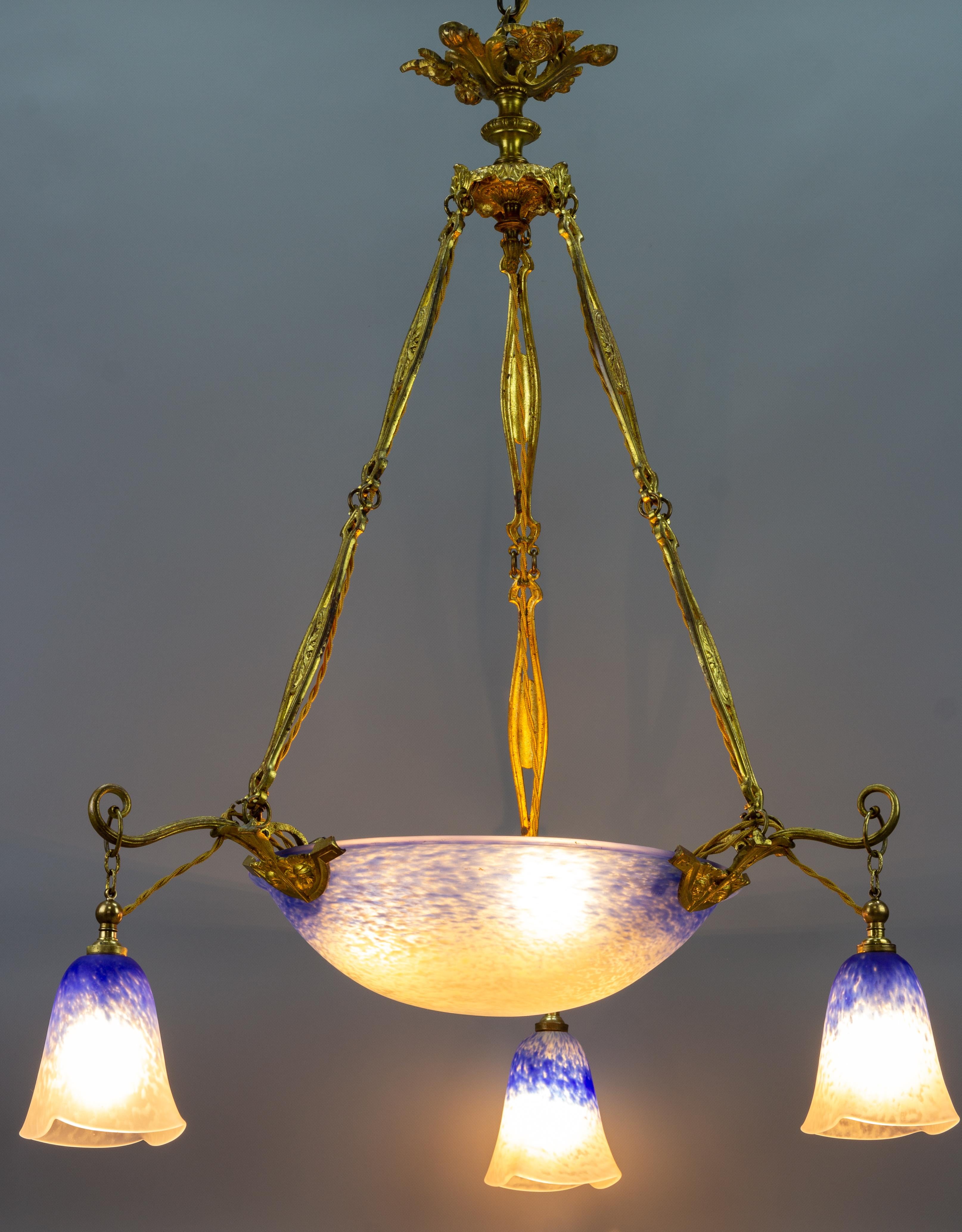 This adorable French Art Nouveau period pendant chandelier features a mottled “Pâte de Verre” art glass shades in blue and white color, signed ”Schneider” by Charles Schneider, hung at an ornate, impressive bronze fixture with roses and foliate