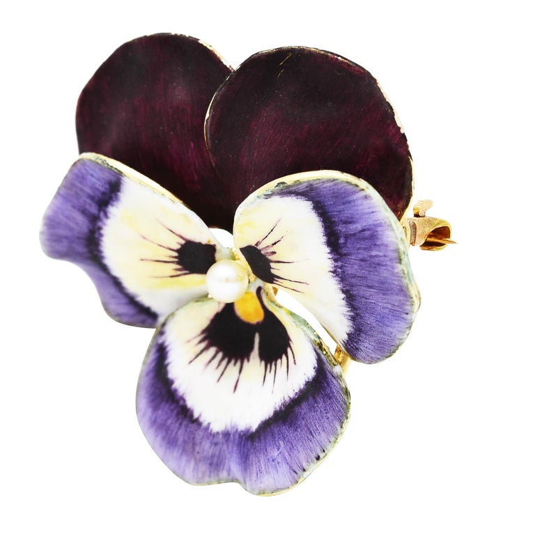 Pendant brooch is designed as a pansy flower with delicately painted matte enamel petals. Opaque purple, maroon, white, and yellow - exhibiting some loss. Centering a 2.5 mm near-round seed pearl. White in body color with moderate iridescence.