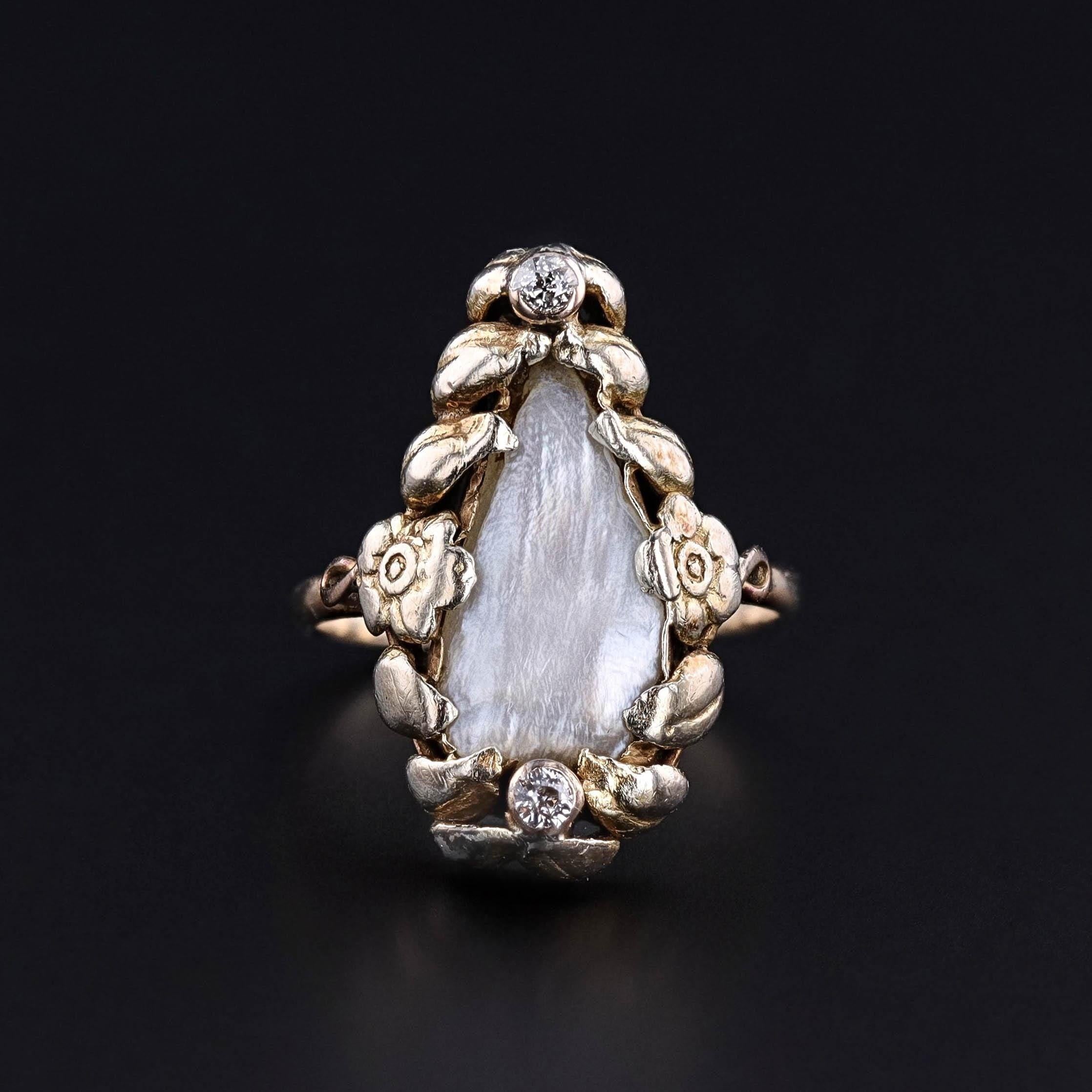 Antiker Perlenring: Dieser Jugendstilring (um 1910) zeigt eine Perle, die in floralem 14-karätigem Gold mit zwei Diamantakzenten gefasst ist.

Das Gesicht des Rings misst 0,85 Zoll mal 0,5 Zoll breit, und es ist in gutem Zustand. Sie hat die Größe
