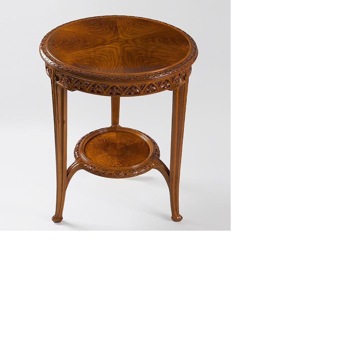 A French Art Nouveau pedestal table by Louis Majorelle. The circular two tier table in beech and walnut wood features carved vegetal motifs in bas-relief. Both the tabletop and the lower shelf are made of beautifully grained wood, circa 1910.
 