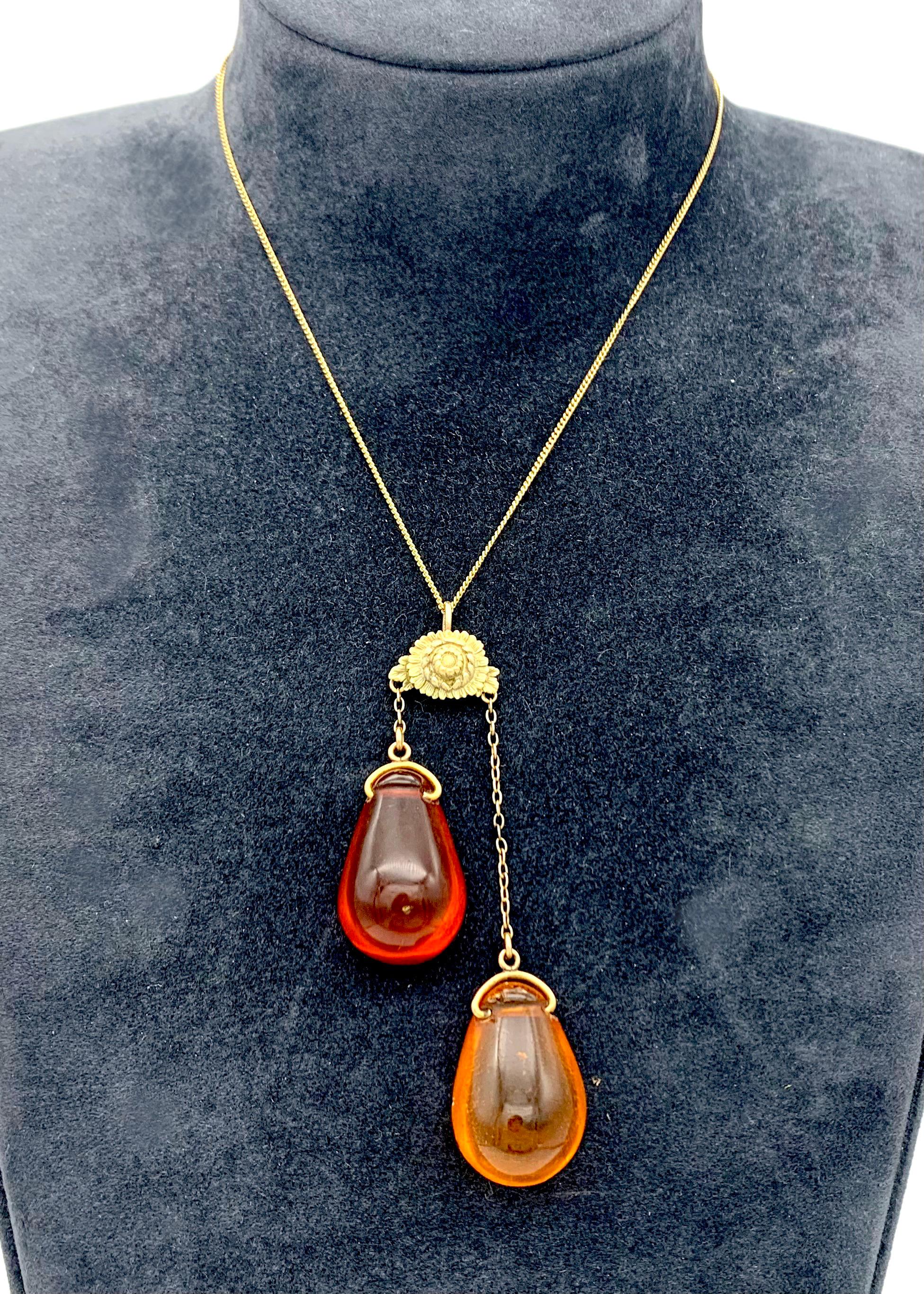This unusual Art Nouveau jewel was created towards the end of the 19th century. From a beautifully modelled chrysanthemum two wonderful thick and sensuous clear and transparent amber drops are suspended. The amber pieces are drilled and are mounted