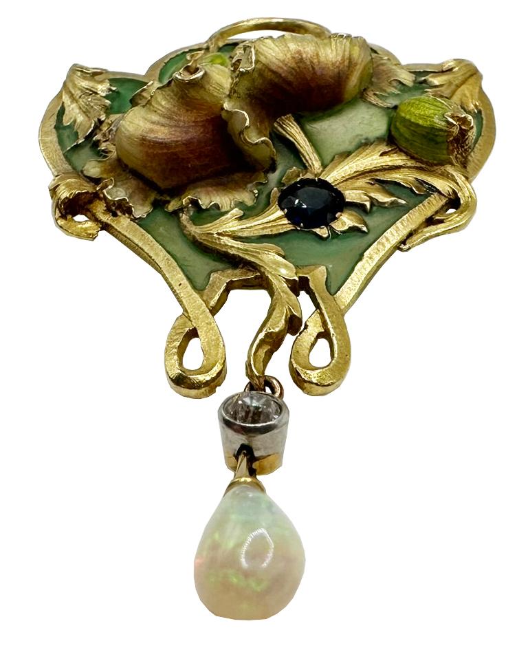 Este exquisito broche, muy detallado, representa un motivo floral de amapolas en oro amarillo de 18 quilates, expertamente esmaltado en un hermoso color verde y decorado con piedras de diamante, rubí y zafiro. El dibujo tiene forma de W y lleva una