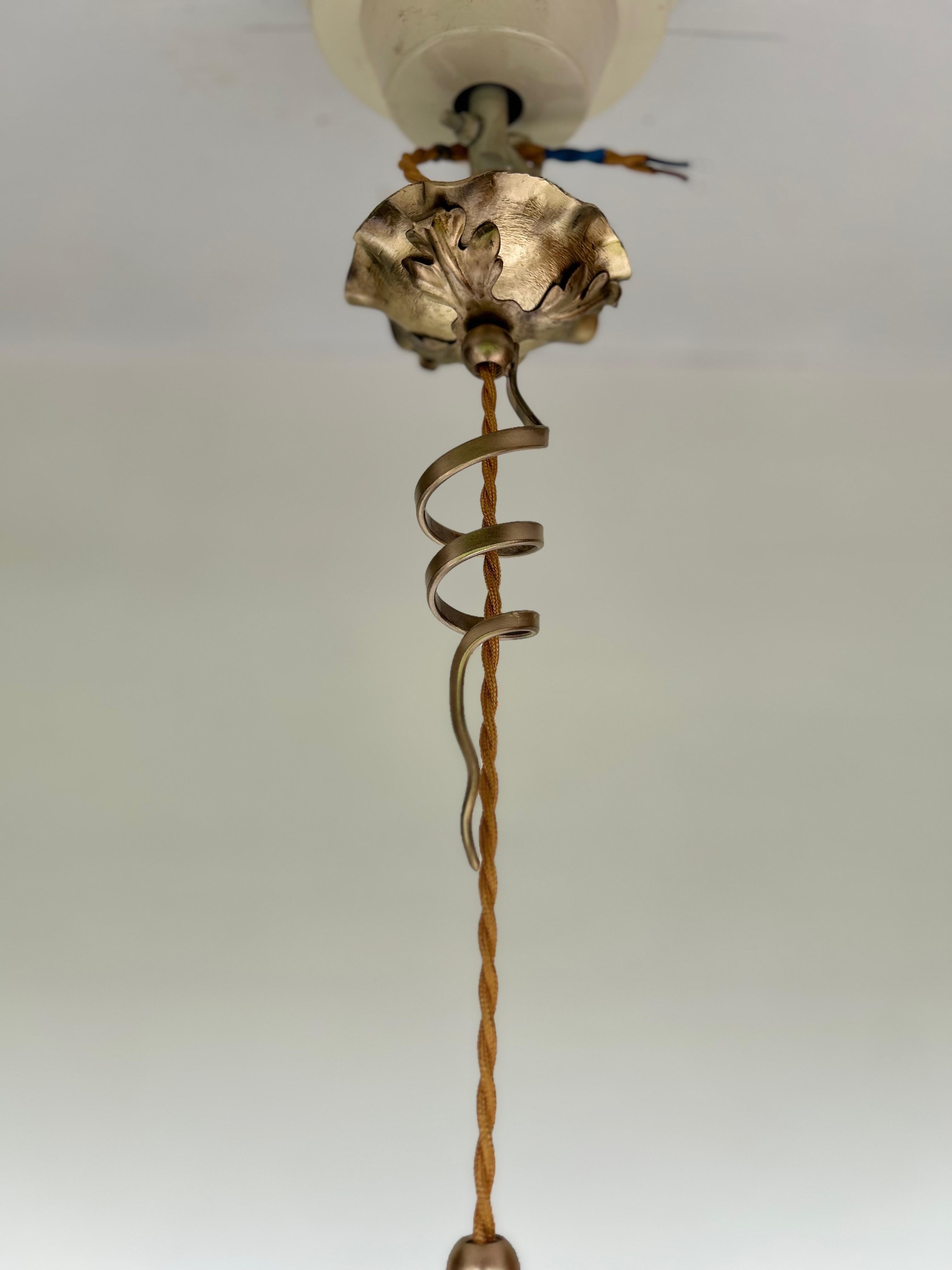 Art Nouveau pendant light circa 1910.
Bronze and brass frame in the style of WAS Benson.
Opalescent glass floral tulip.
Electrified, 1 light, E14 socket, LED screw bulb.

Height: 45 cm (height is adjustable)
Diameter: 14cm
Weight: 800g